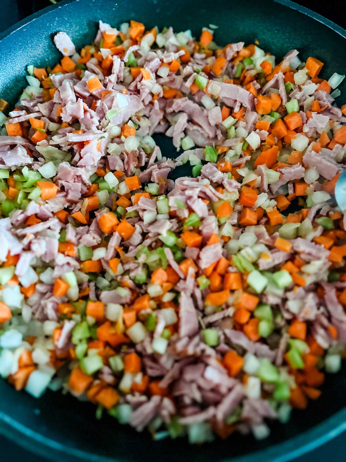 Close up photo of bacon, onion, carrot, and celery that are ready to cook in a skillet.