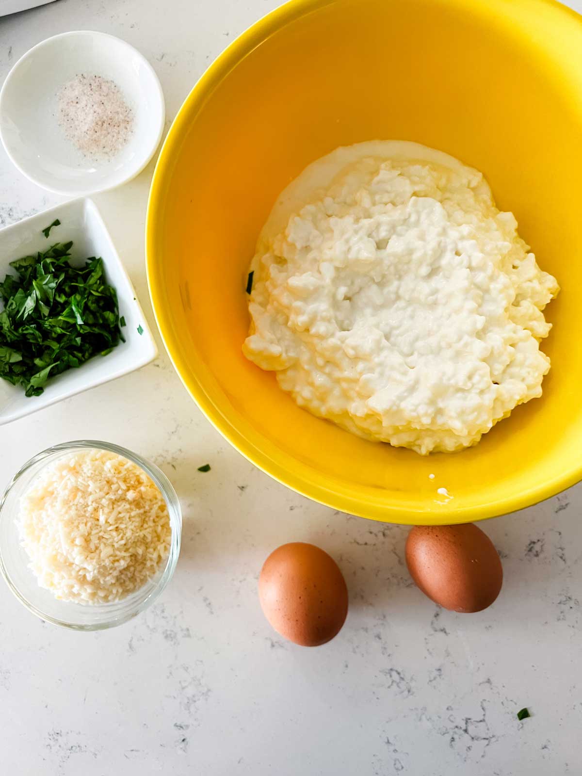 Overhead photo of the cottage cheese mixture for lasagna: cottage cheese, egg, parmesan, parsley, and salt.