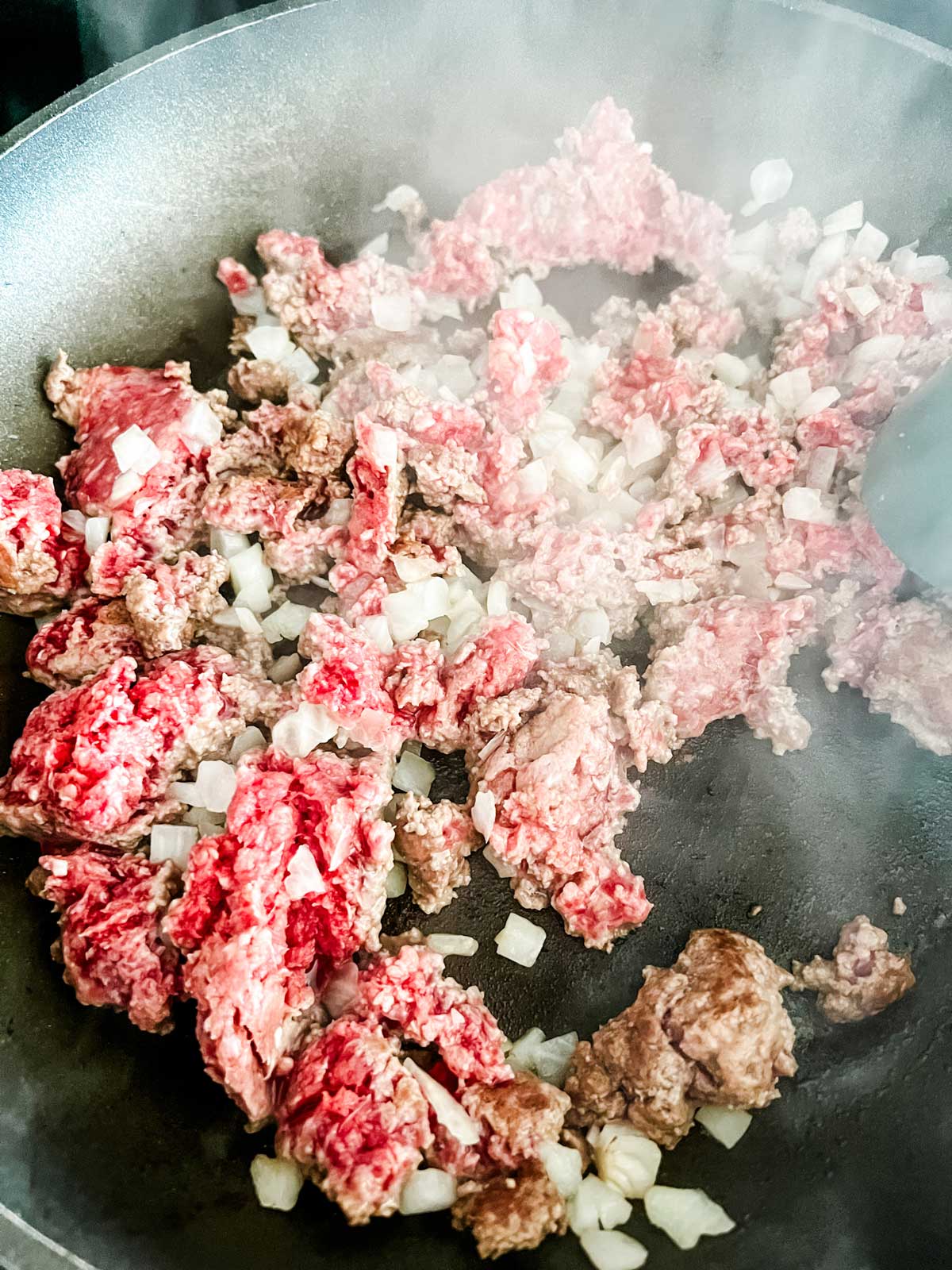 Ground beef and onion cooking in a skillet.