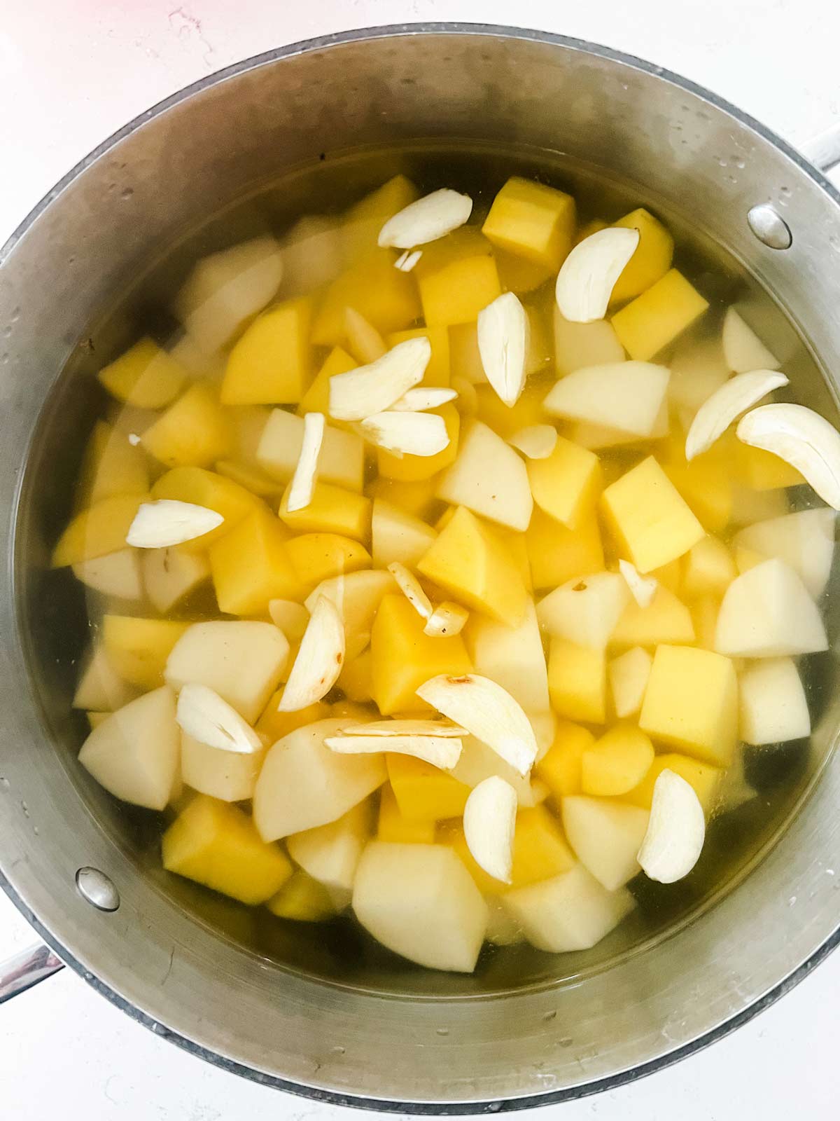 Diced potatoes and garlic in a pot of water.