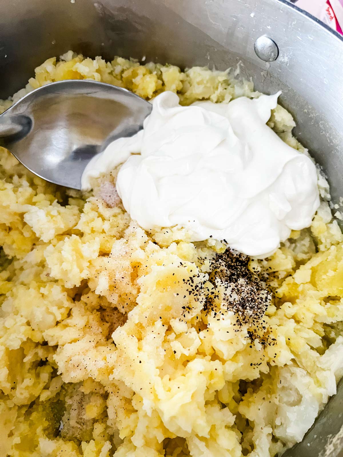 Mashed potatoes with sour cream being stirred in.