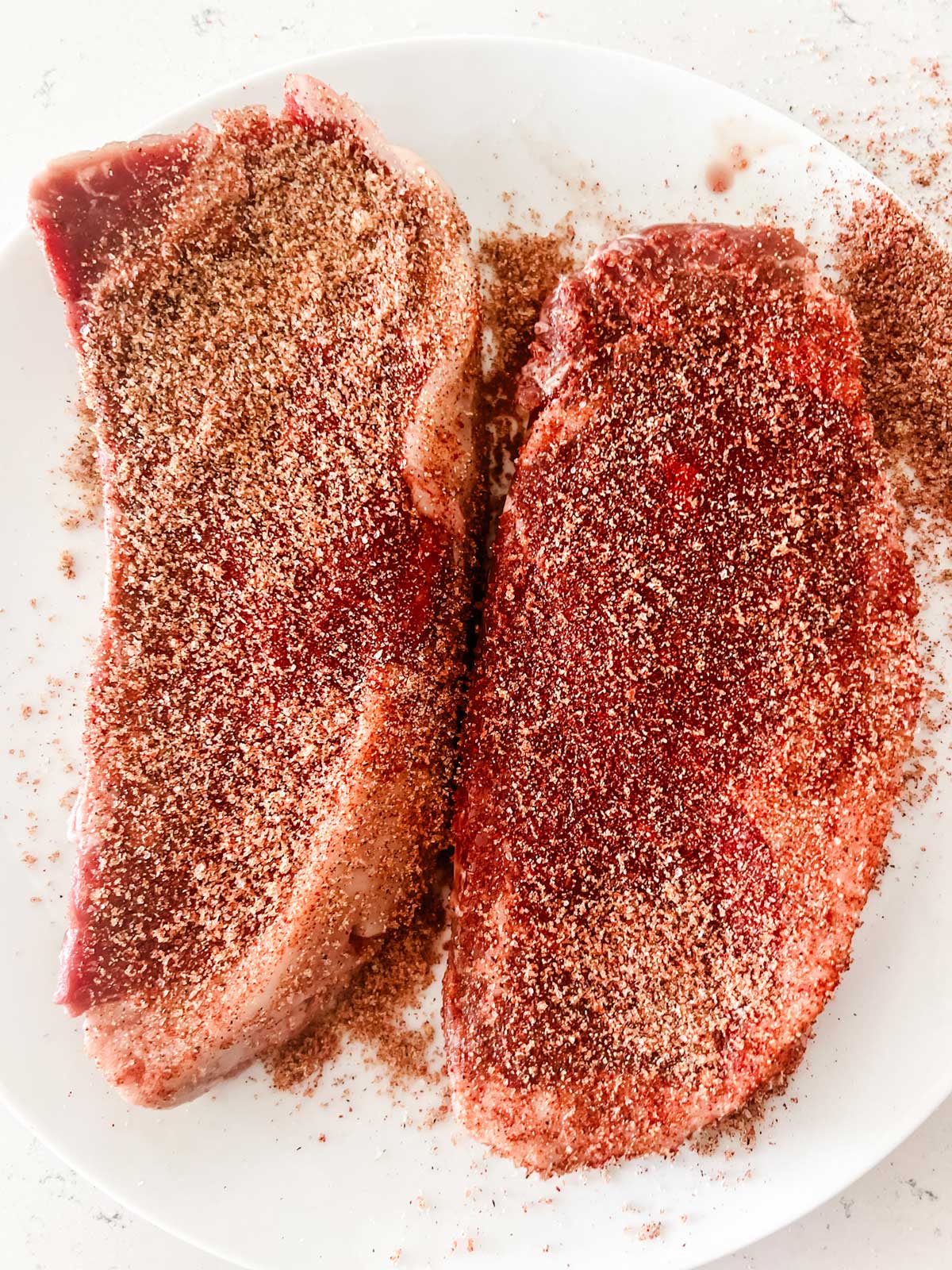 Photo of Ninja Foodi Steaks that have been seasoned and are resting on a plate.