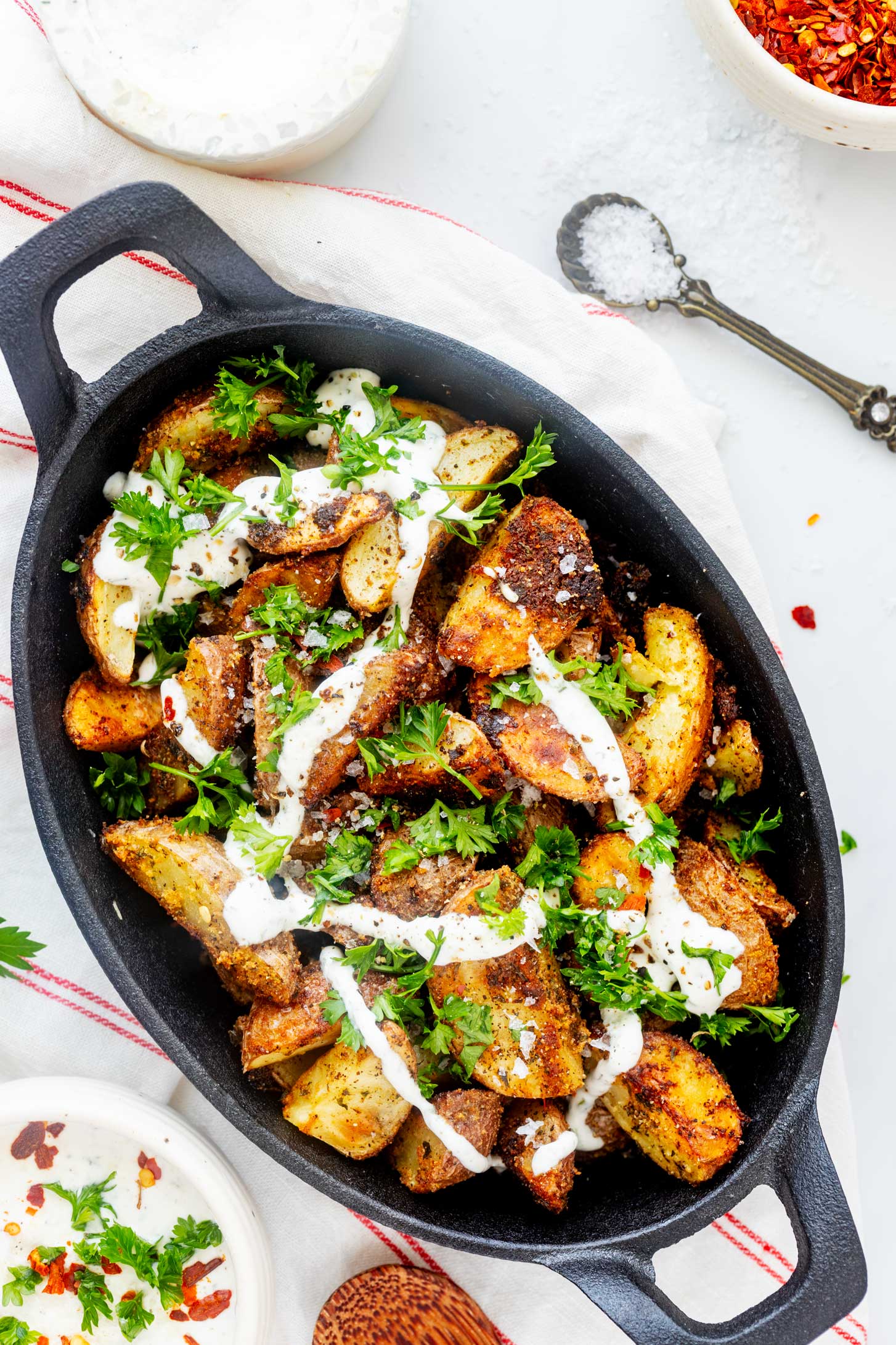Overhead photo of ranch potatoes in a cast iron dish drizzled with ranch dressing.