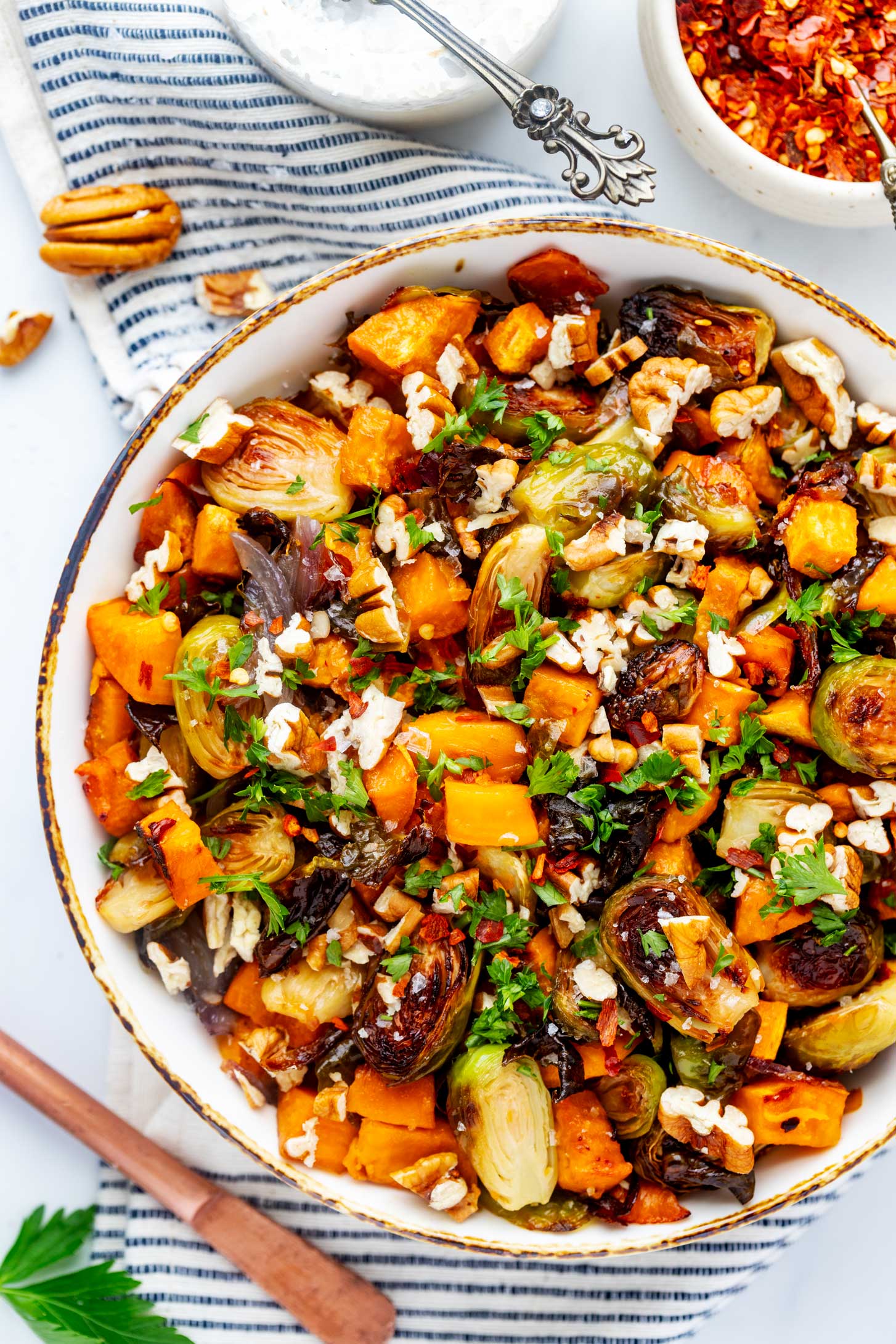 Close up overhead photo of roasted Brussels sprouts and sweet potatoes in a rustic bowl.