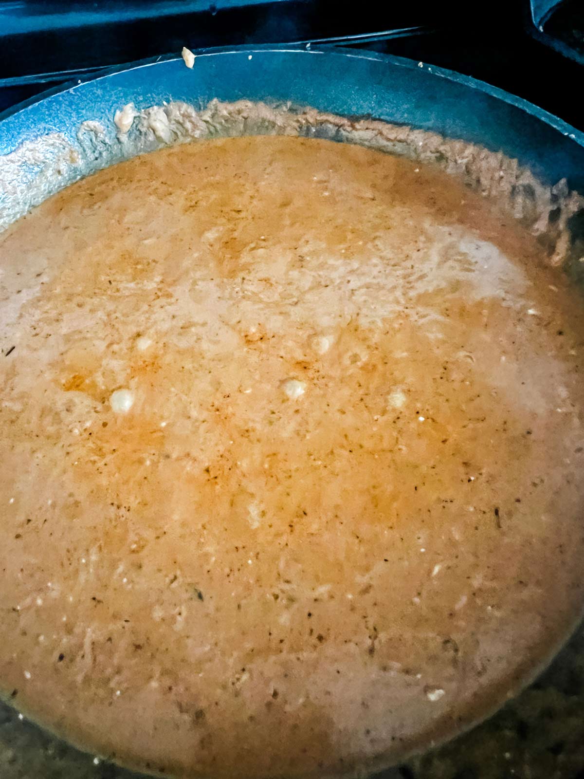 A creamy enchilada sauce cooking in a skillet.