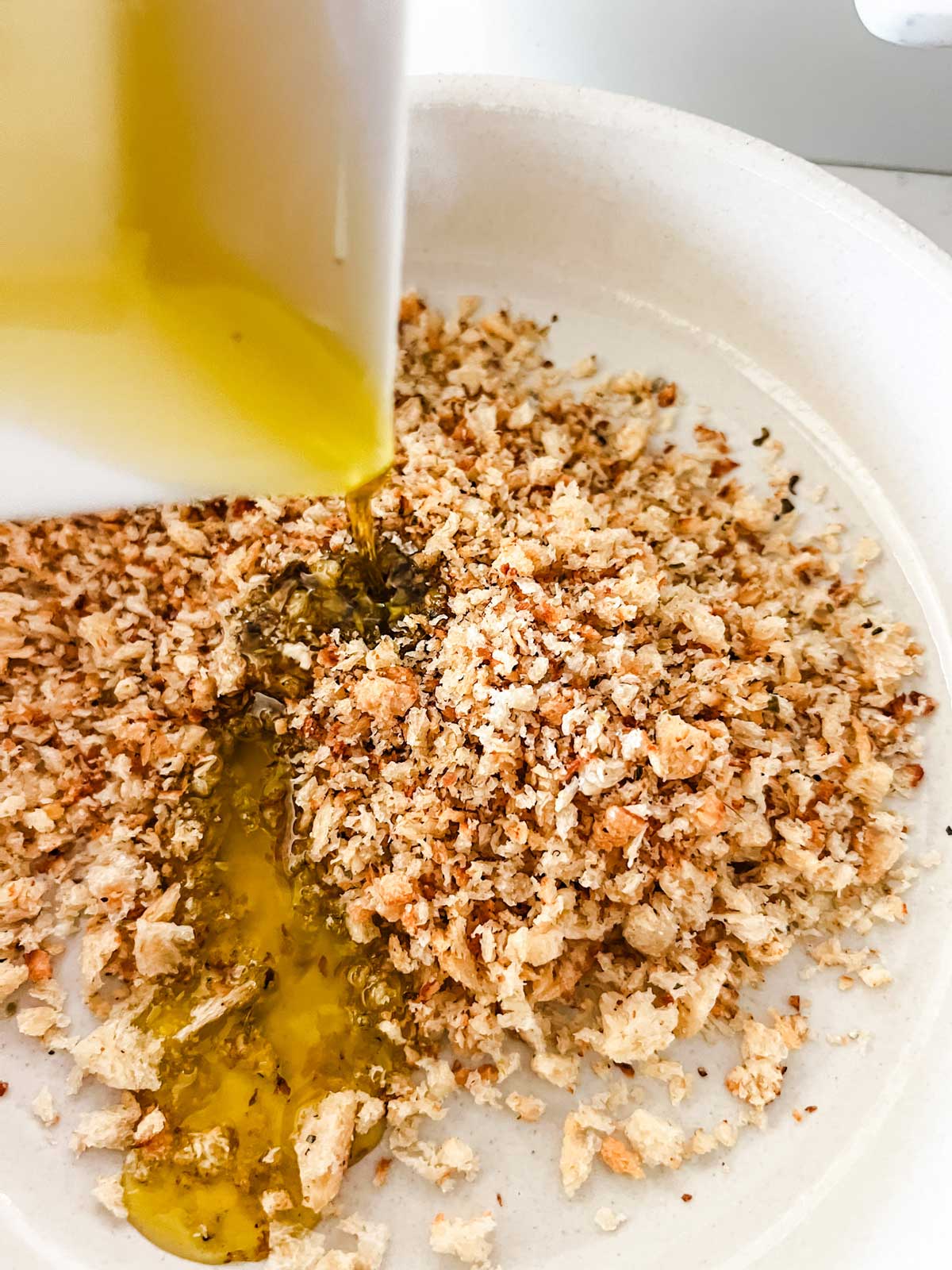 Oil being mixed with breadcrumbs.