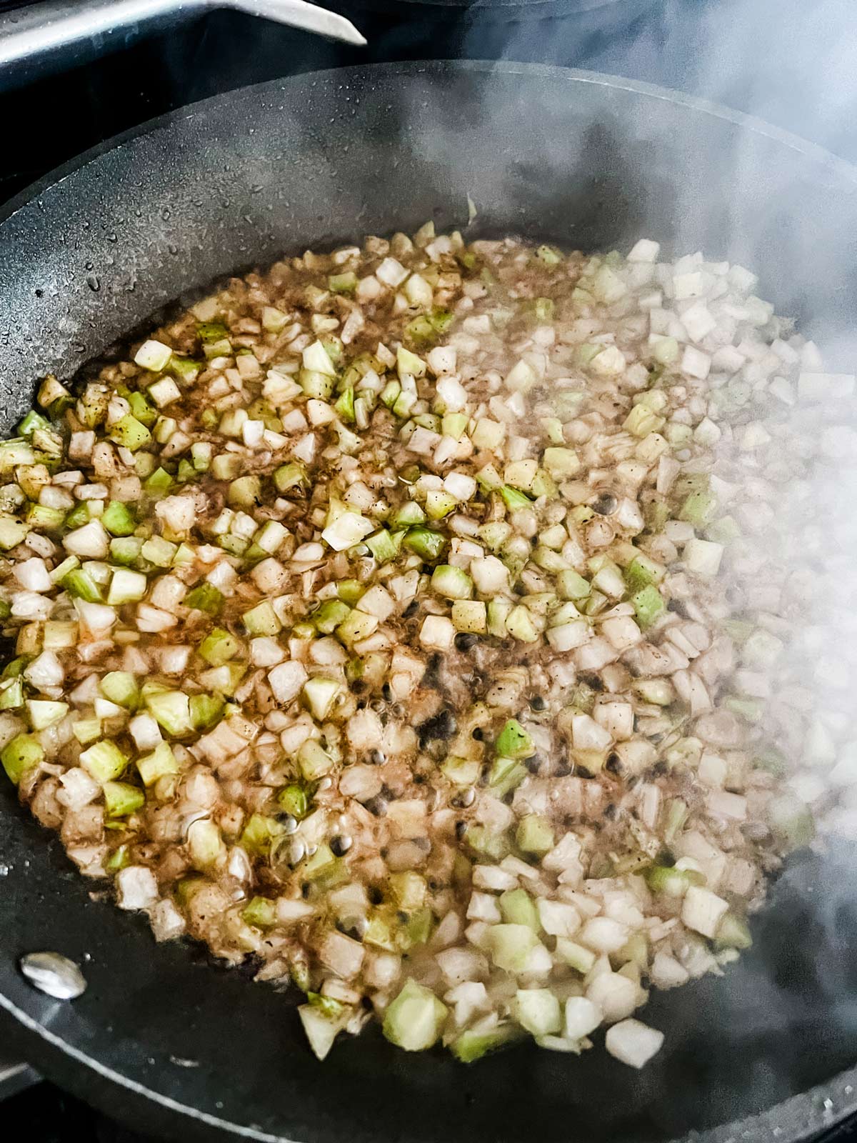 Onion and celery cooking in a skillet.
