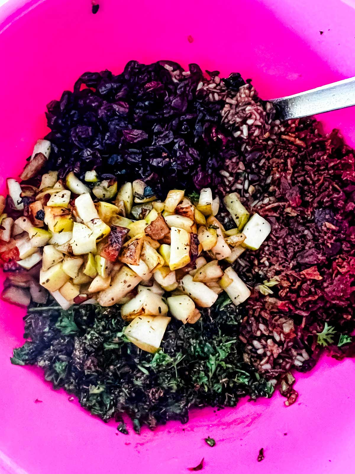Wild rice, cranberries, apple, and parsley in a large pink bowl.