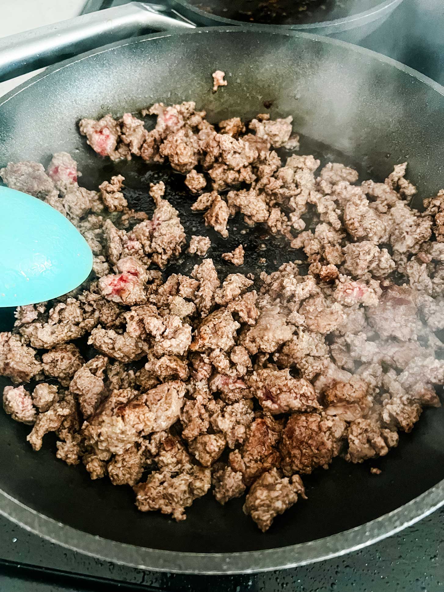 Ground beef cooking in a skillet.