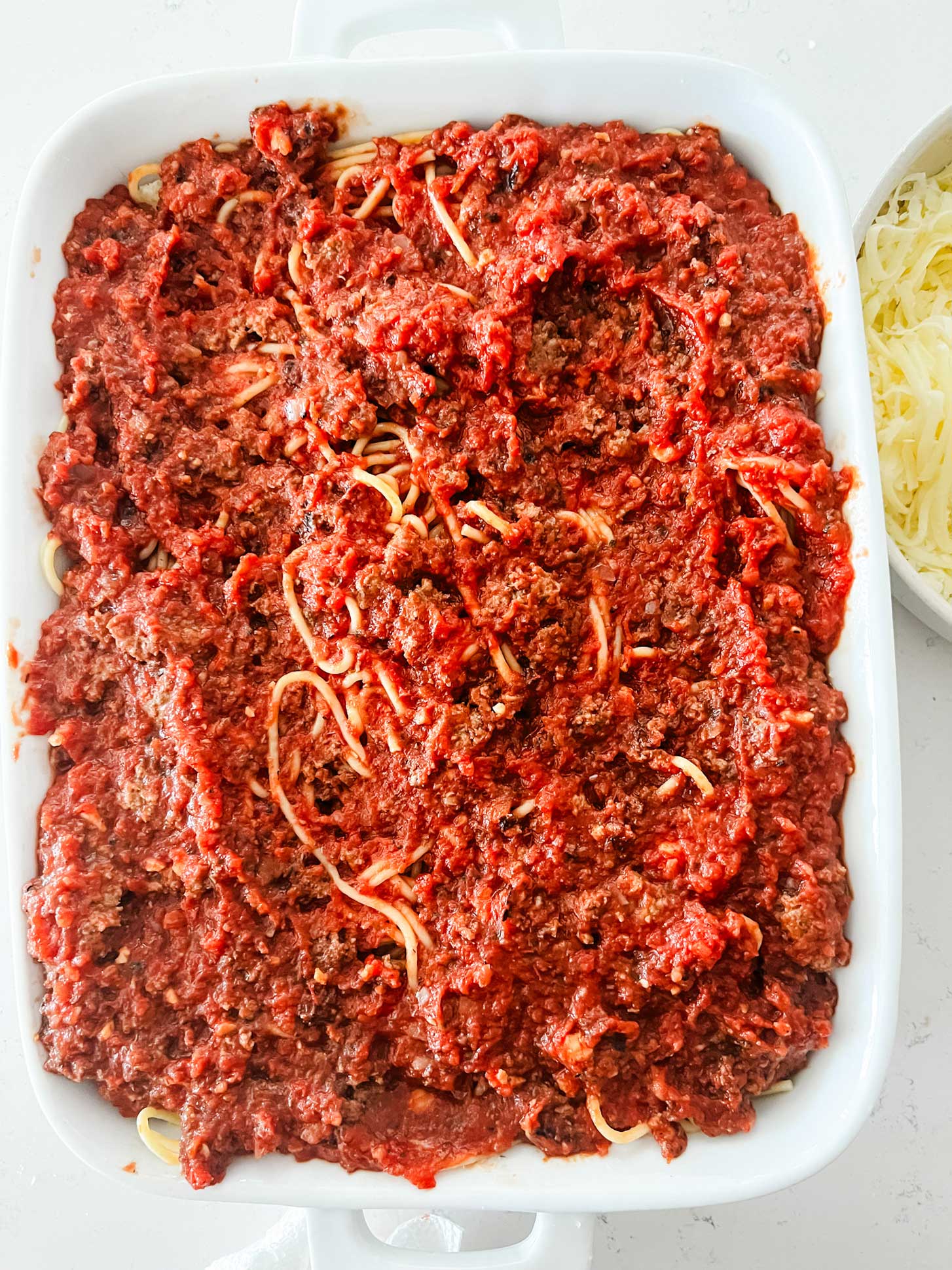 Meat sauce layered on top of a baked spaghetti.