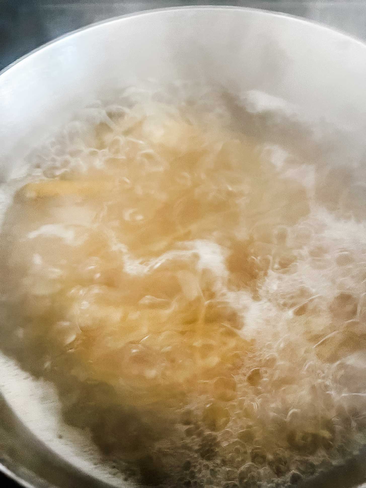 Spaghetti noodles boiling in a large pot of water.