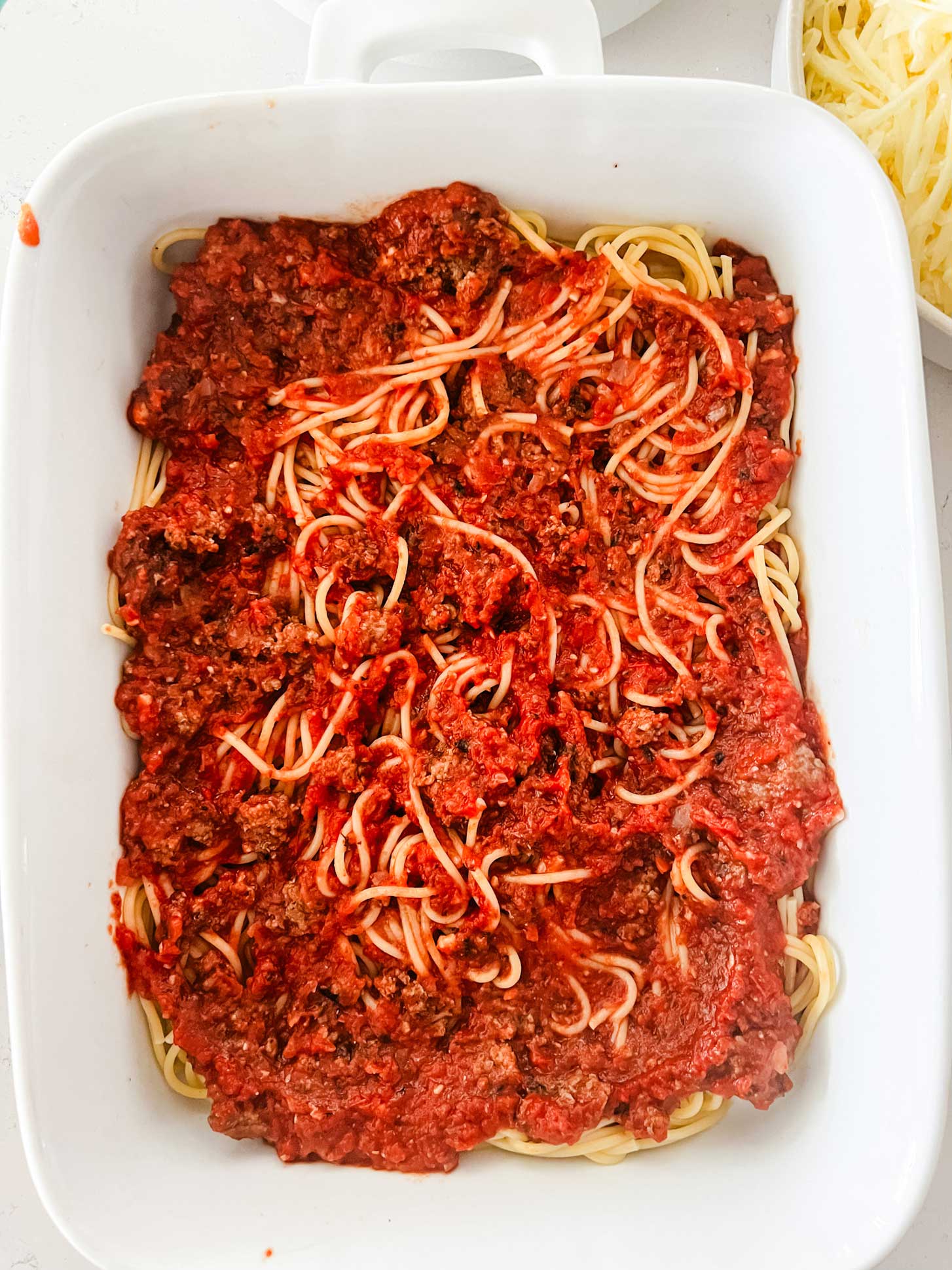Overhead photo of a casserole dish with spaghetti noodles and meat sauce.