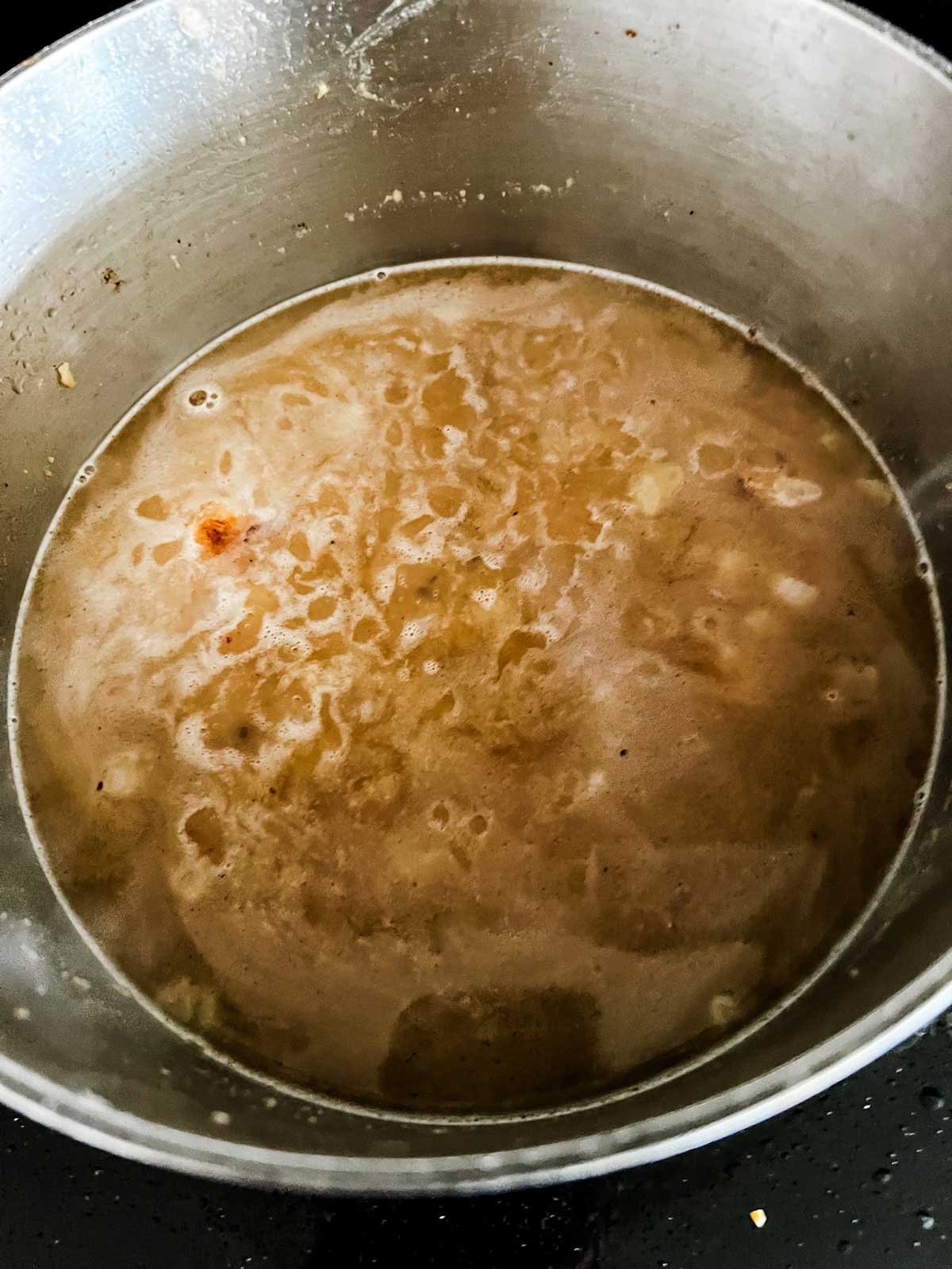 Broth added to butter, onion, and flour in a pan.