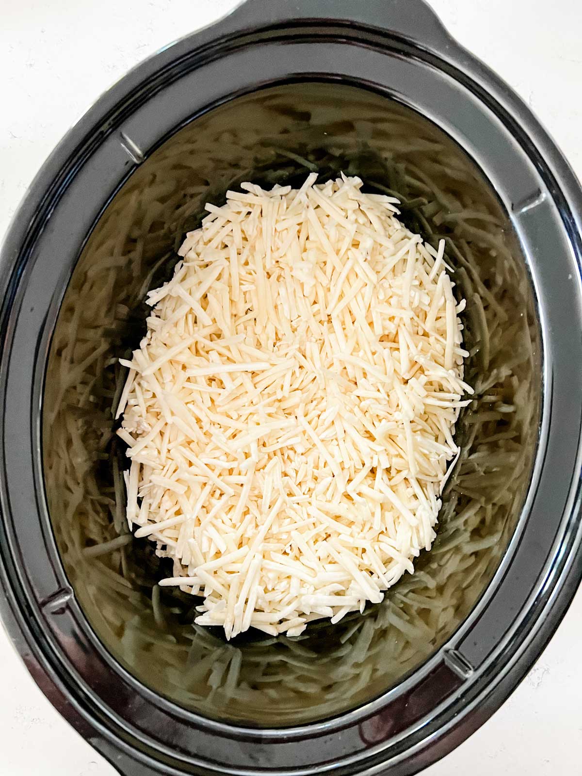 Hash browns in the bottom of a slow cooker.