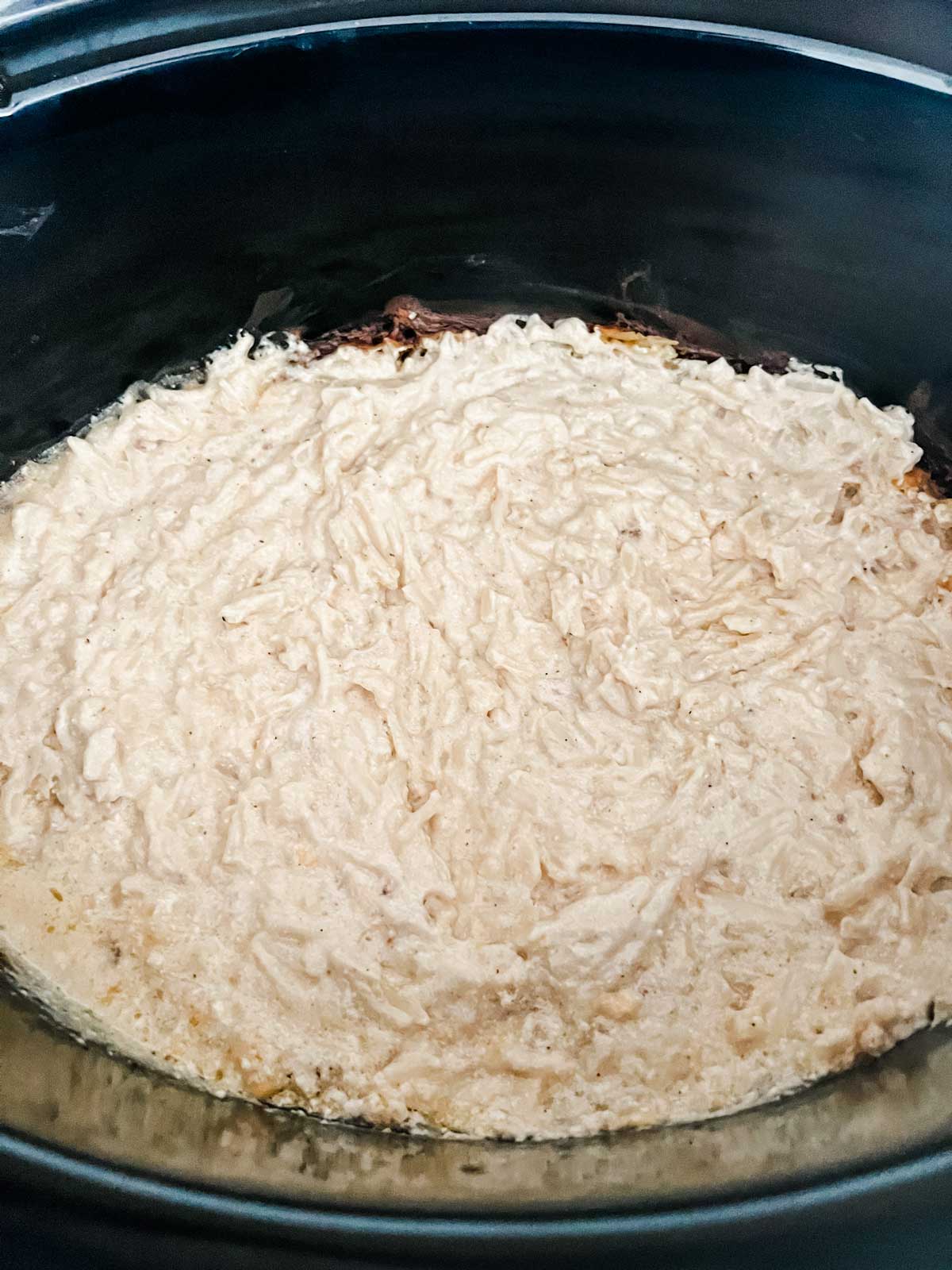 Hash browns in a creamy sauce in a slow cooker.