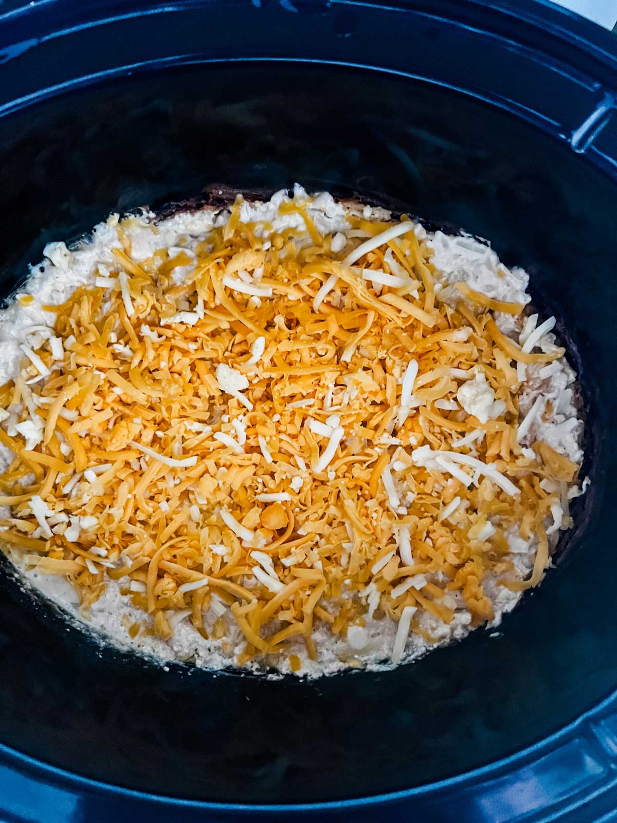 Crockpot cheesy hash brown casserole in a slow cooker ready to cook.