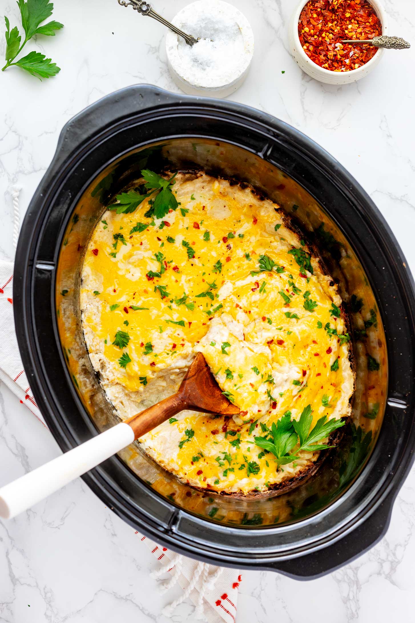 Overhead photo of a hash brown casserole in a crockpot with a spoon.
