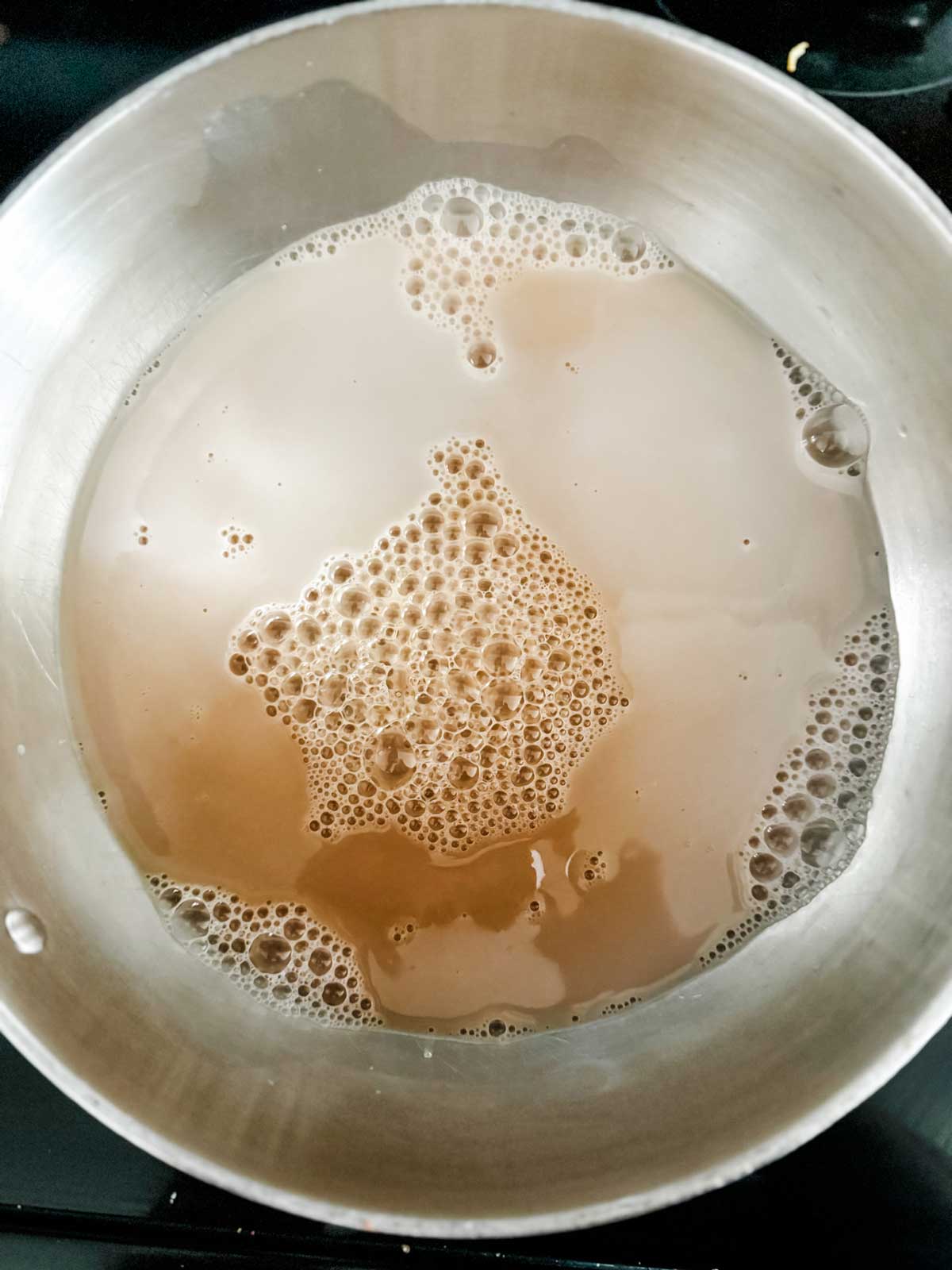 Chai latte concentrate and milk in a saucepan.