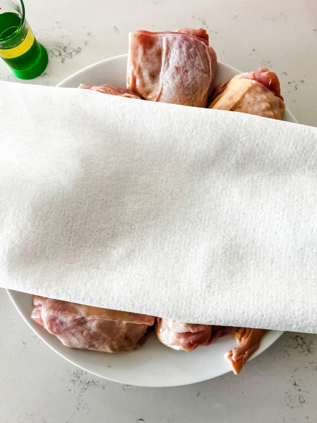 Chicken thighs being dried off with paper towels.