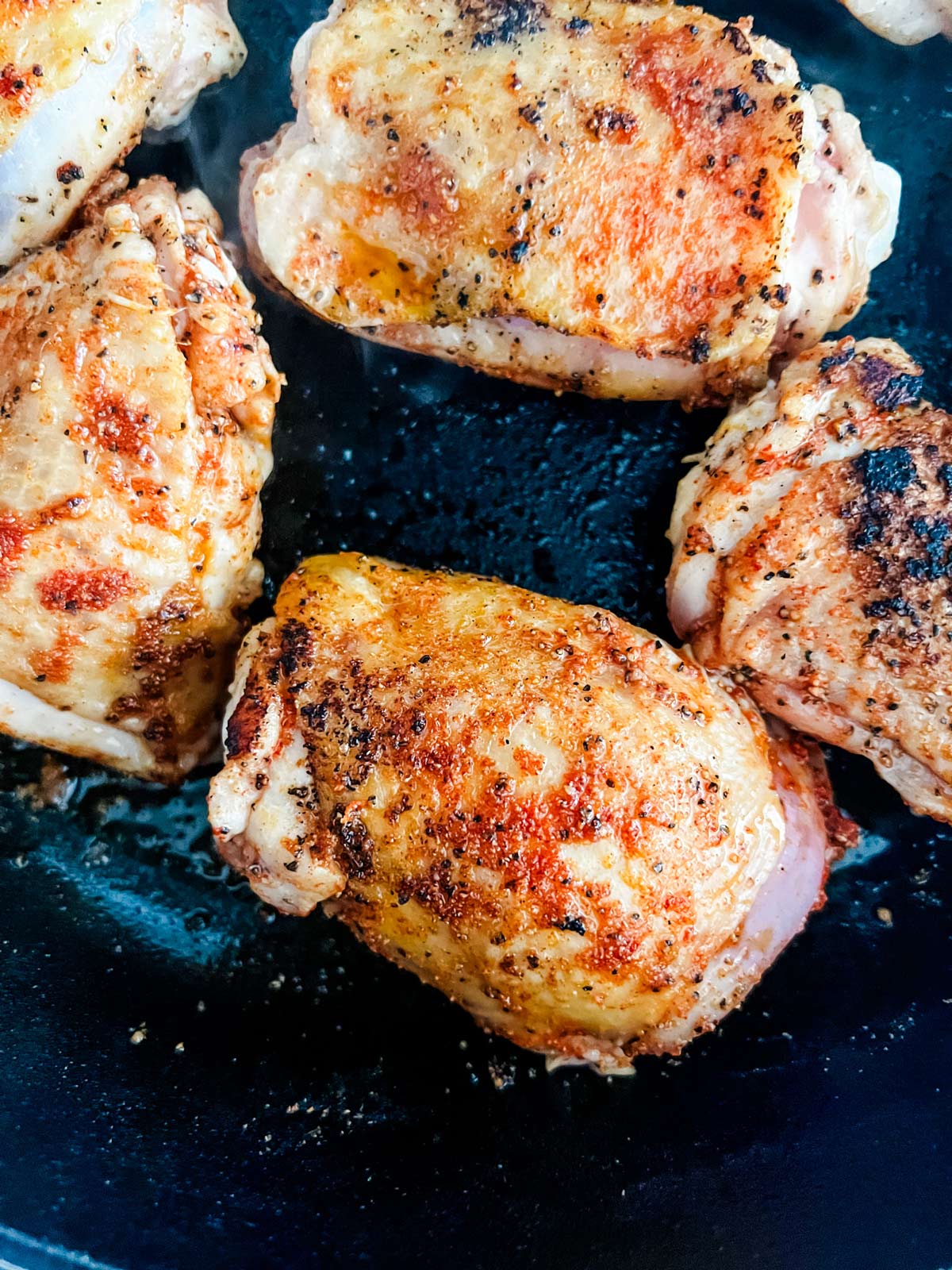 Chicken thighs in a cast iron skillet.