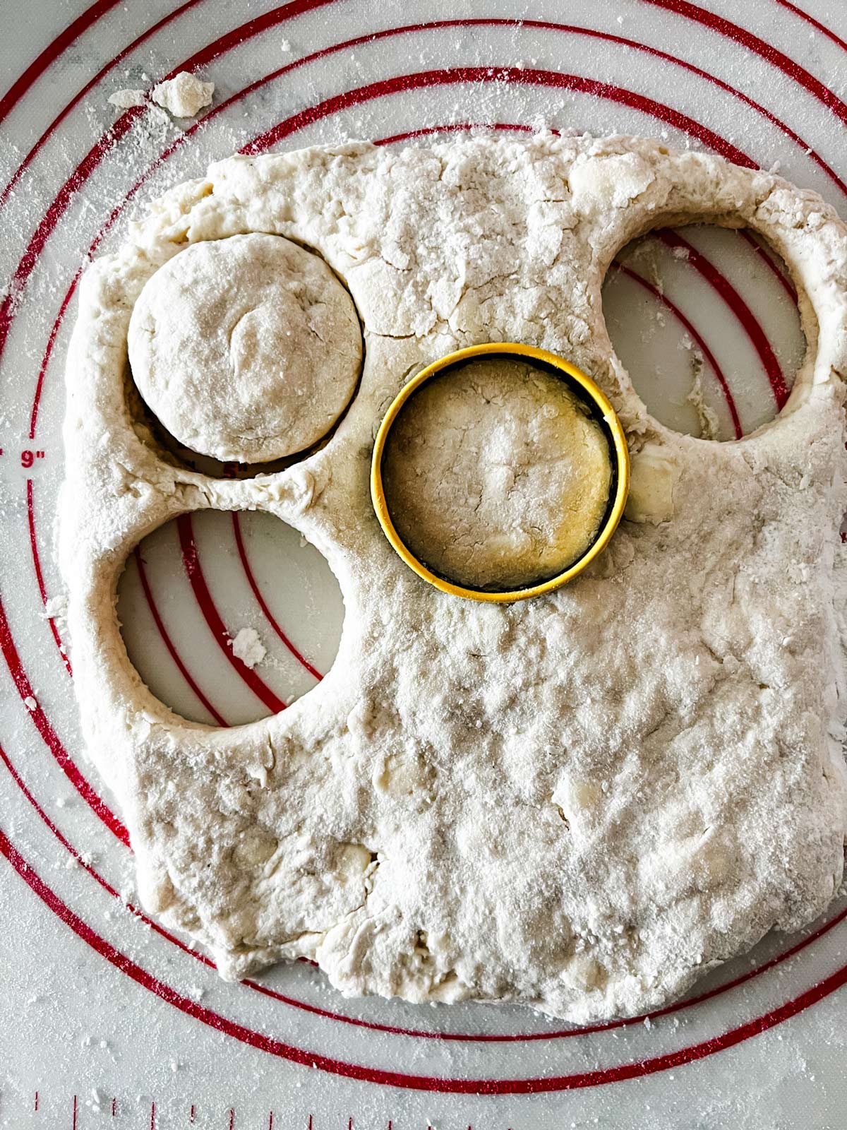 Overhead photo of air fryer biscuit dough that have been rolled out and are being cut.