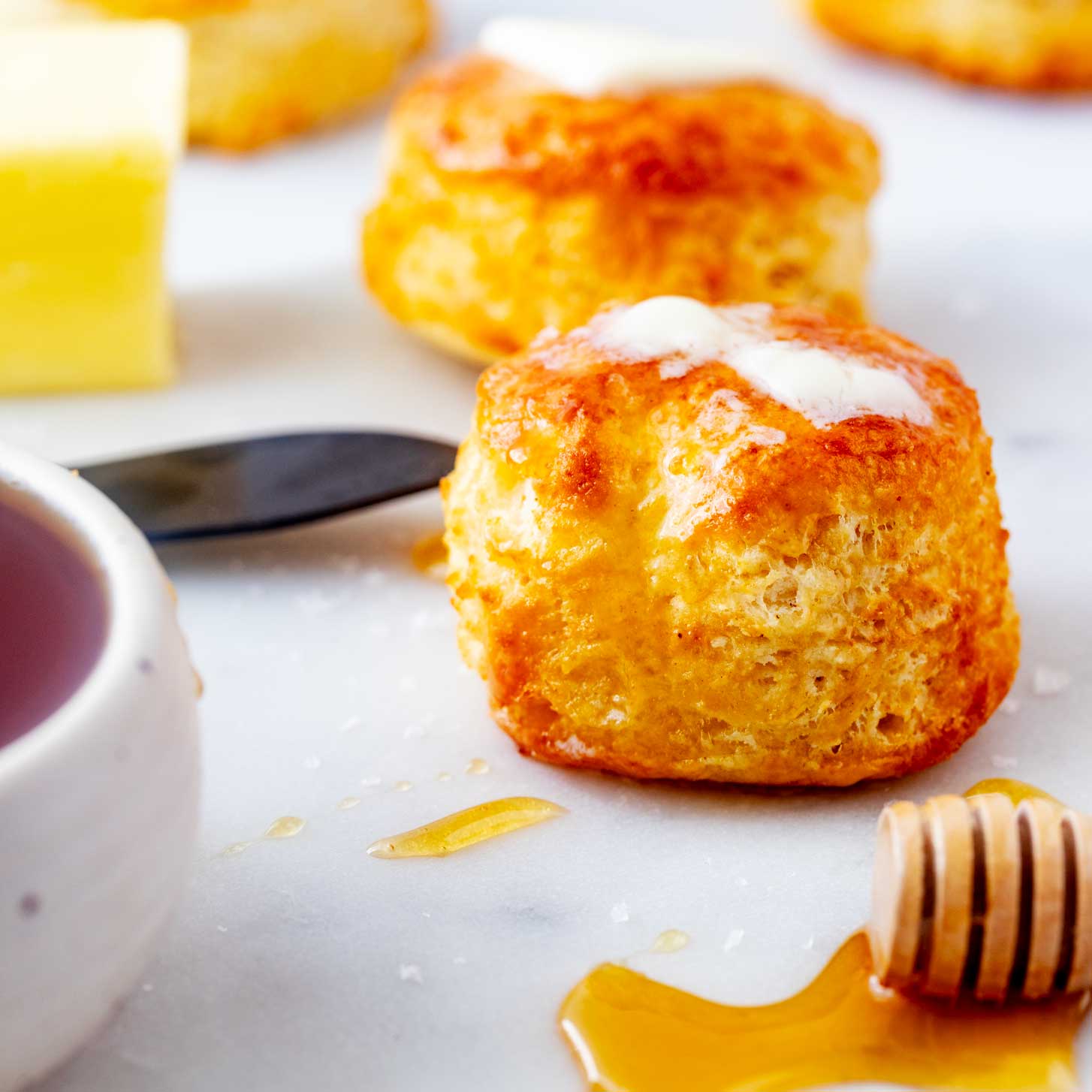 Square side photo of air fryer biscuits on a white surface.