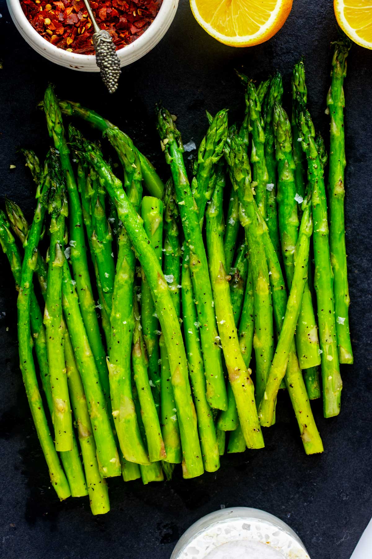 Air fryer asparagus just removed from the air fryer and placed on a slate board.