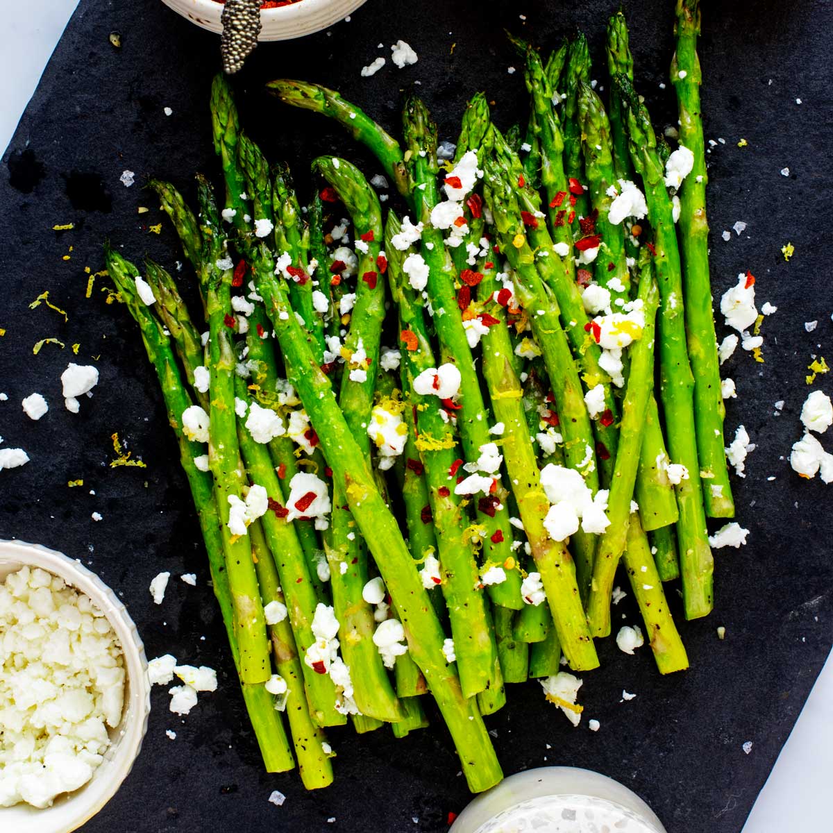Square overhead photo of air fryer asparagus with goat cheese on a slate platter.