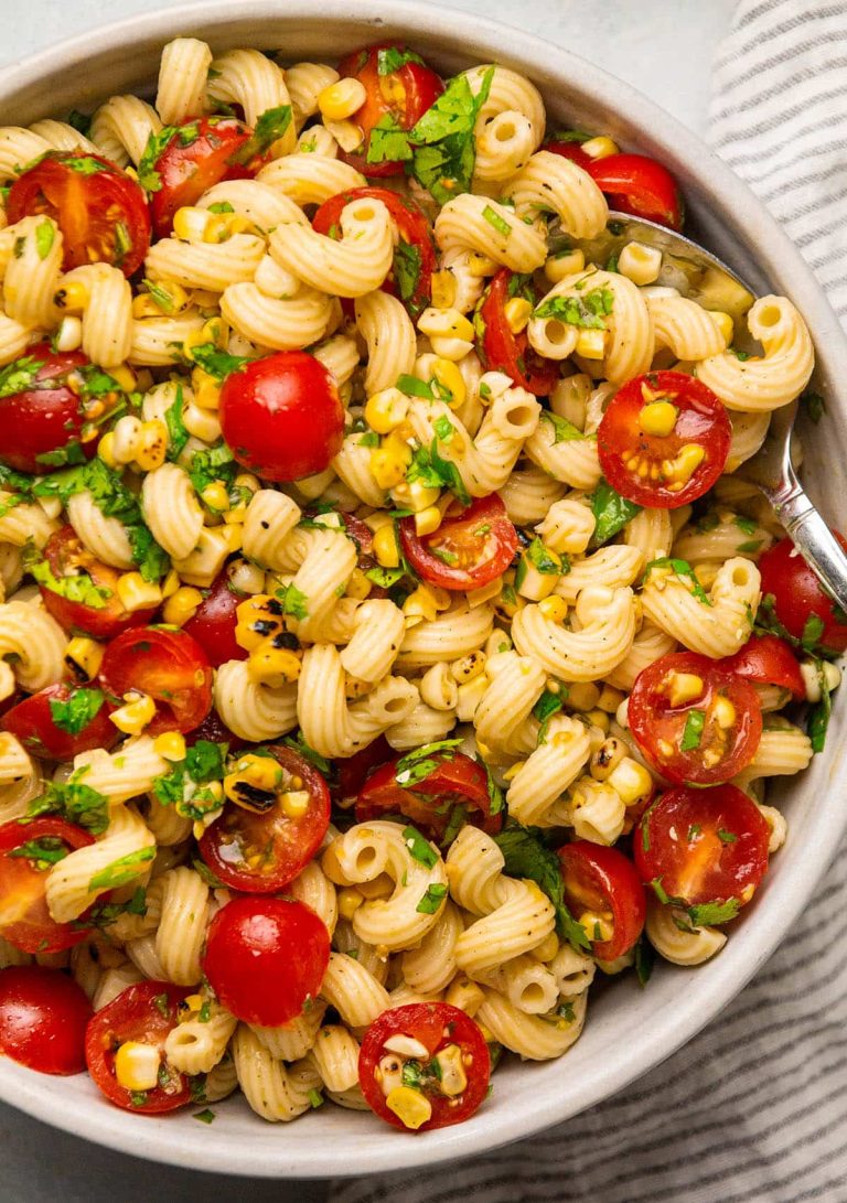 Close up photo of a summer pasta salad with corn and tomatoes.