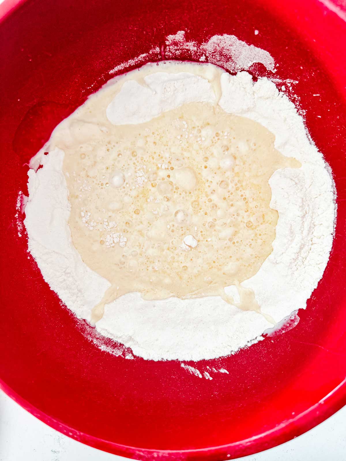 Dry ingredients in the bottom of a bowl with the wet ingredients just being added to it.