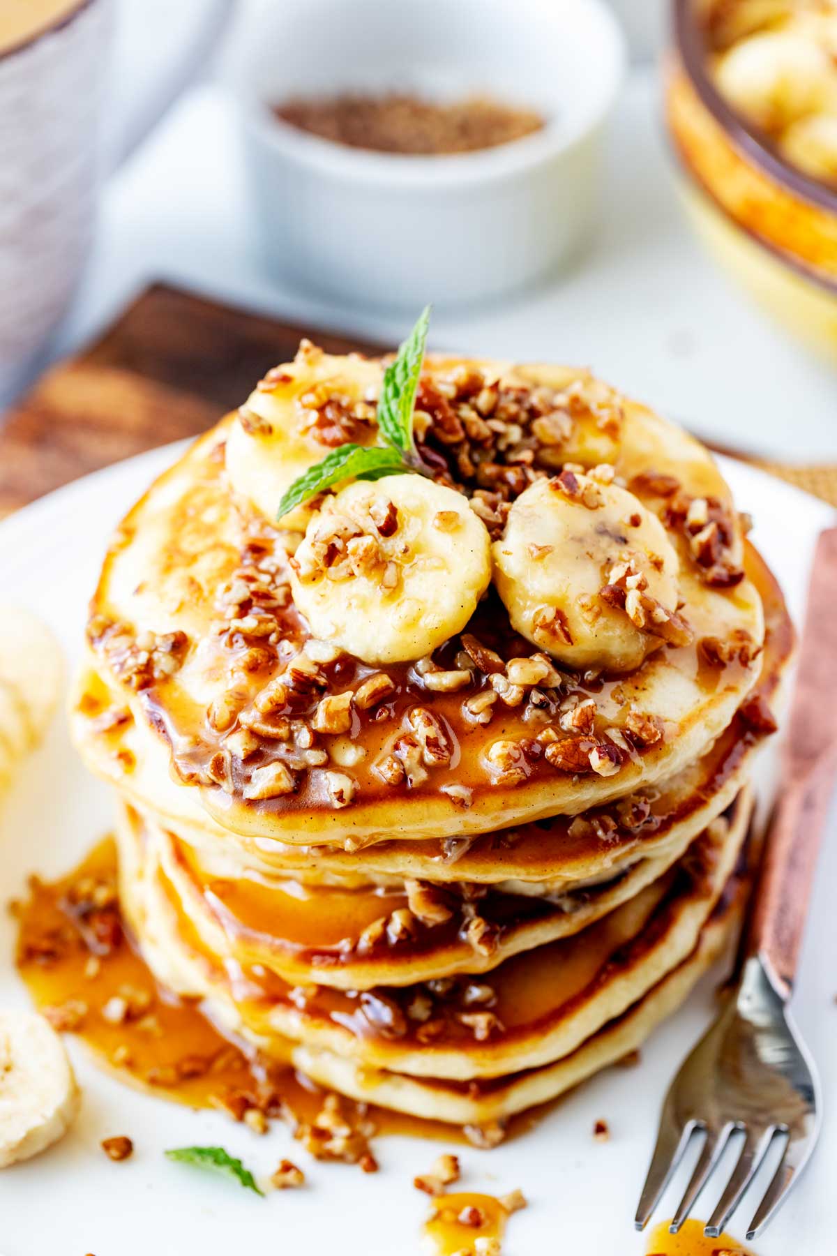 Close up photo of a stack of Blackstone pancakes on a white plate with banana sauce.