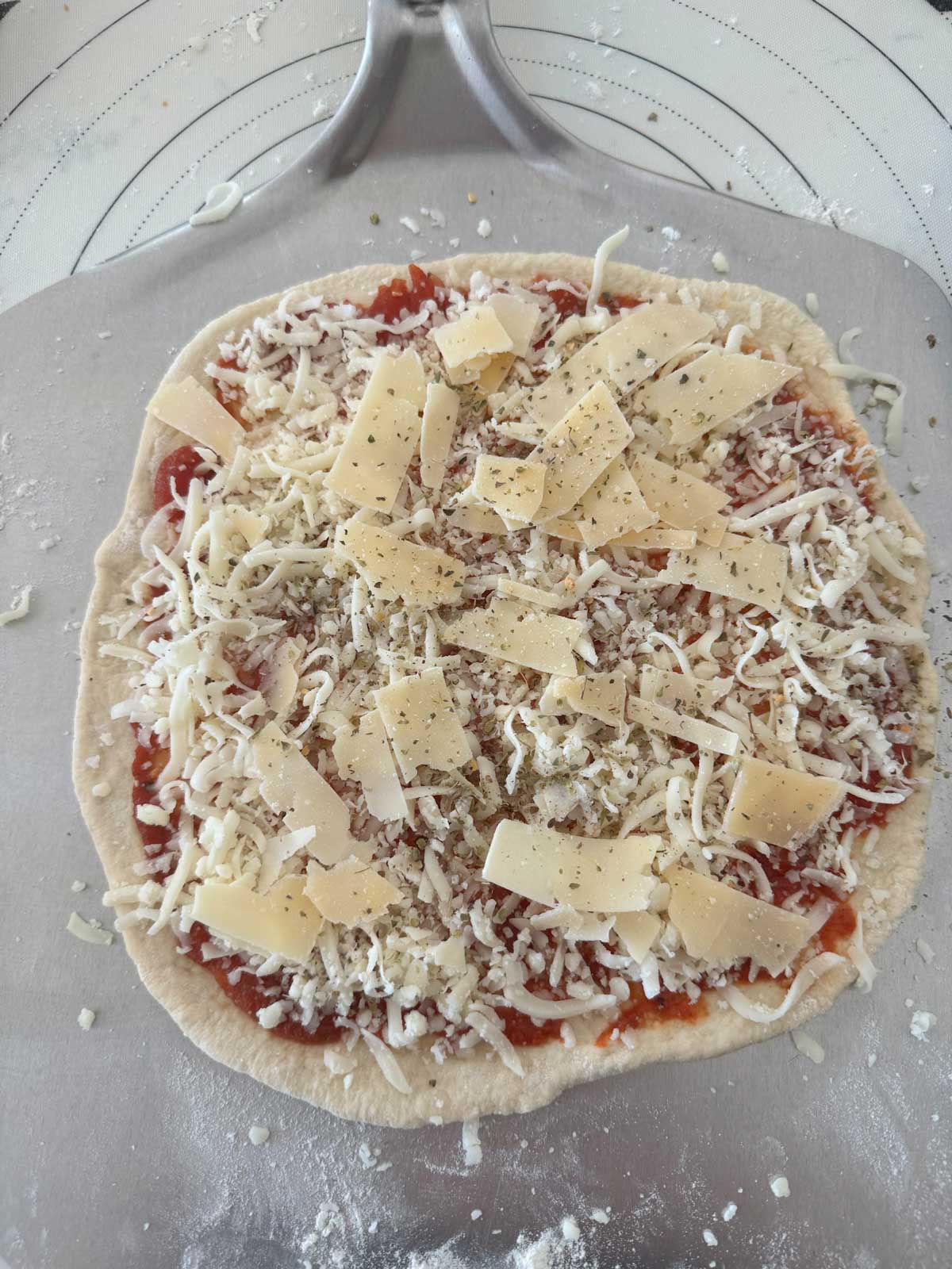 A cheese pizza on a pizza peel ready to bake.