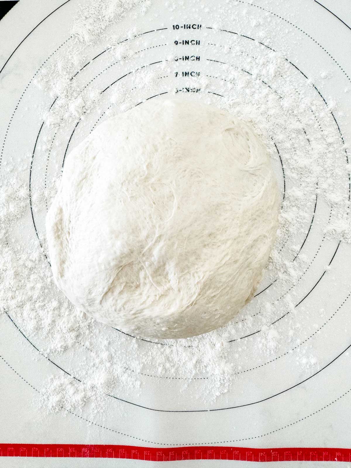 Photo of pizza dough on a floured pastry mat.