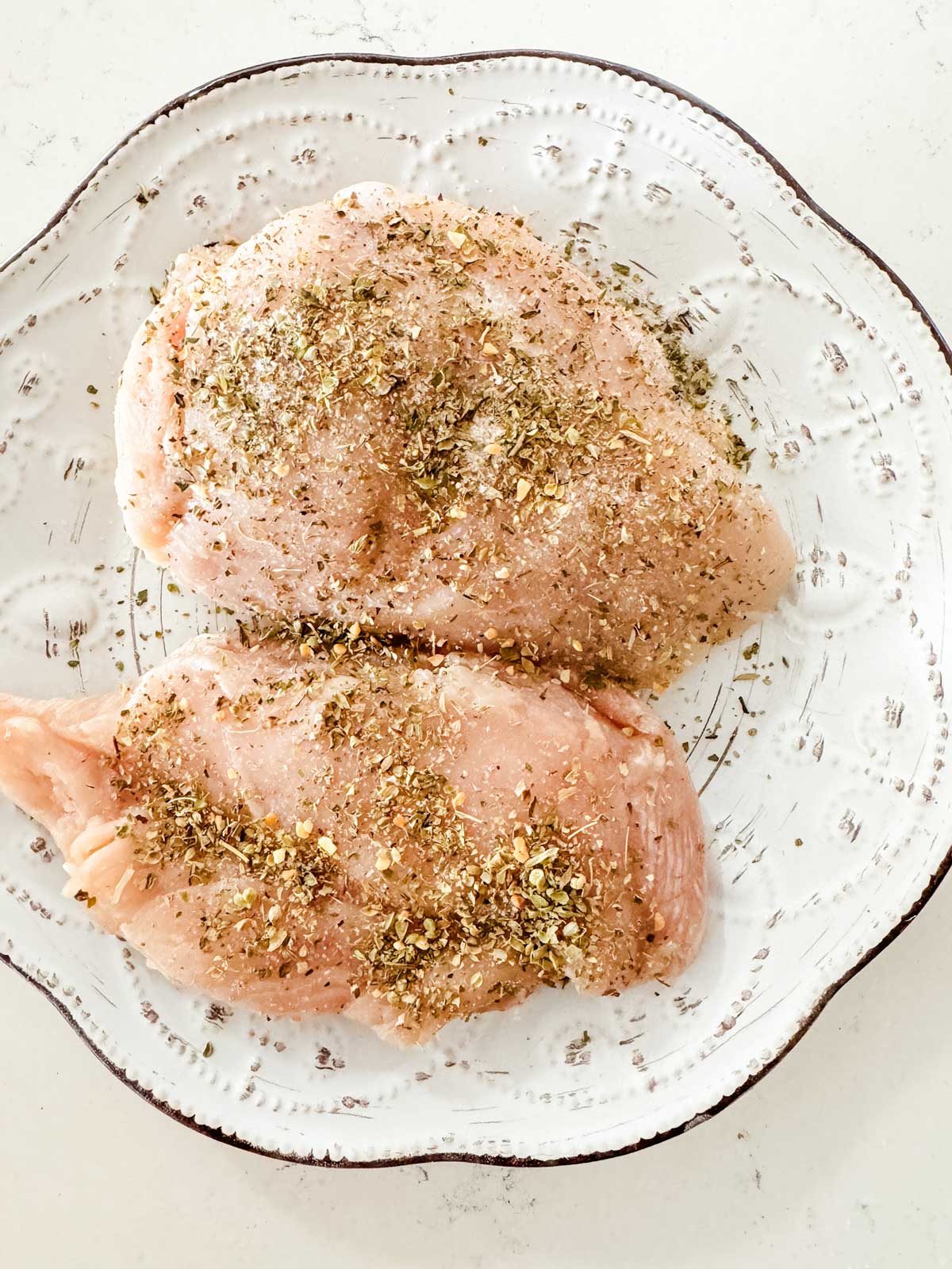 Raw seasoned chicken on a small plate.