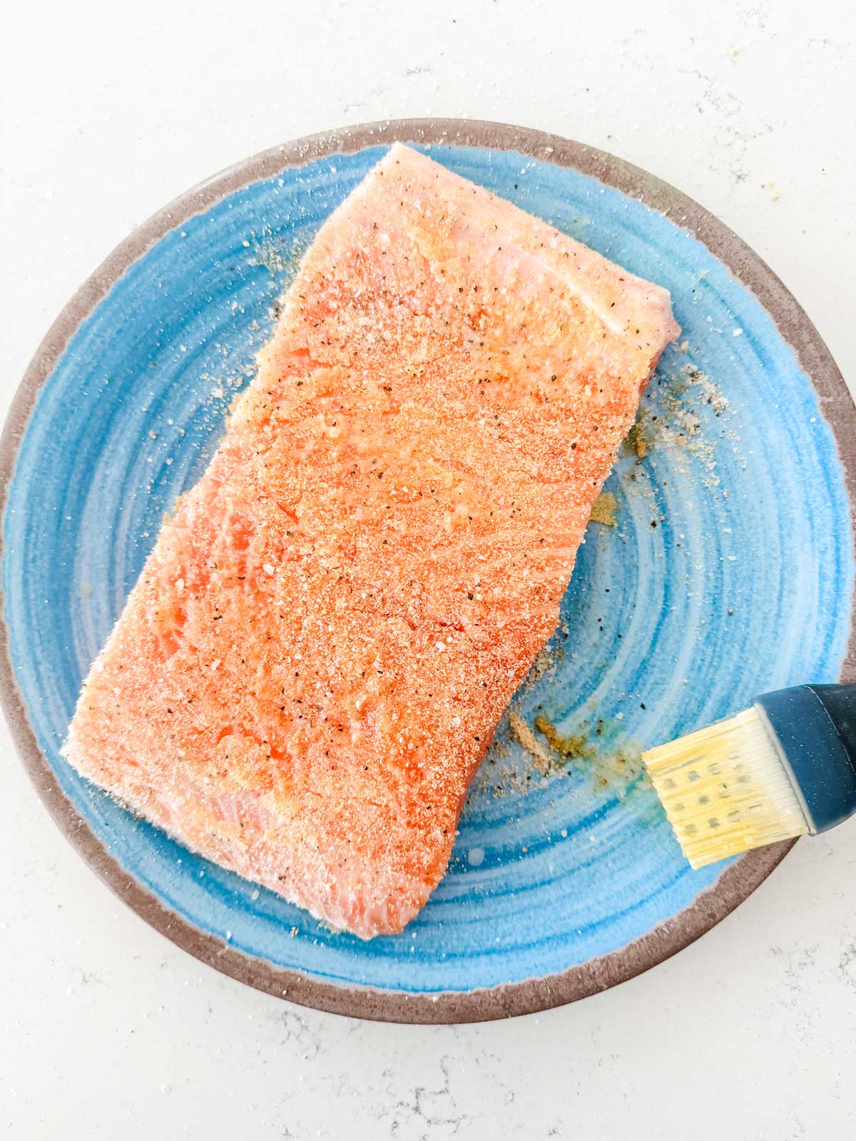 Seasoned salmon sitting on a light blue plate.