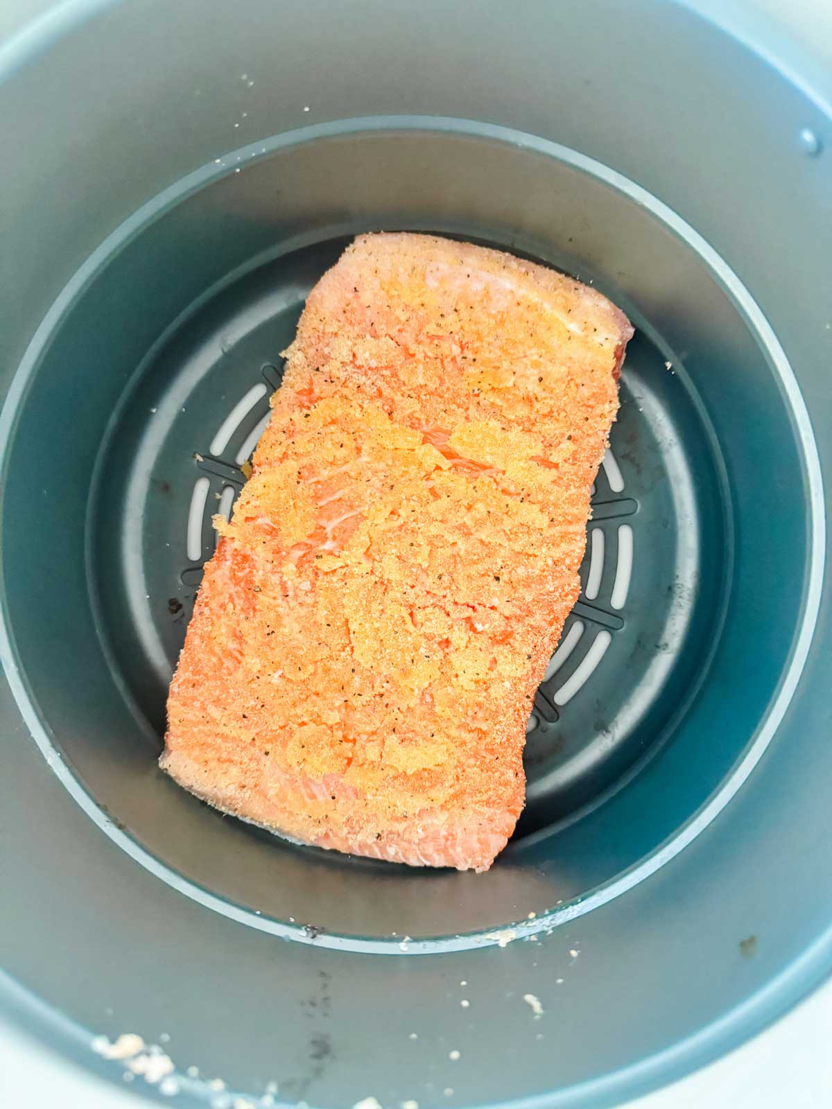 Raw salmon in an air crisp basket of a Ninja Foodi.