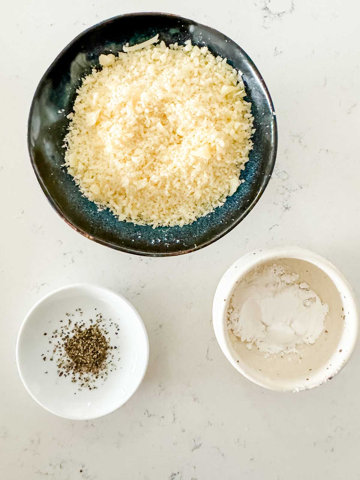 Overhead photo of finely grated parmesan, pepper, and arrowroot powder.