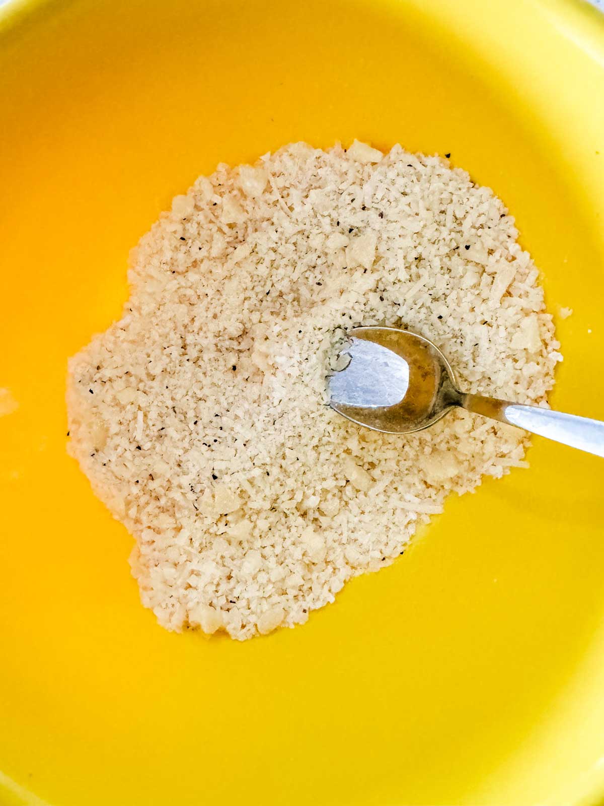 Parmesan cheese, pepper, and arrowroot powder in a yellow bowl.