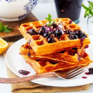 Square side photo of high protein waffles with blueberry compote on top.