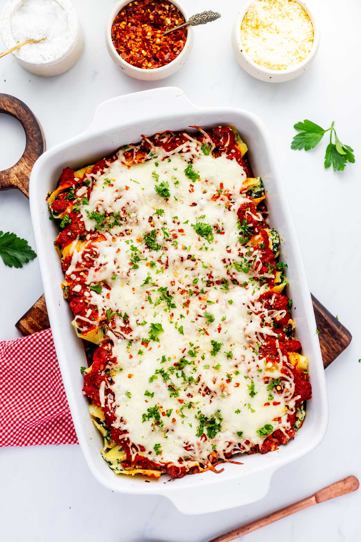 Overhead photo of a white casserole dish with stuffed shells with meat sauce in it.