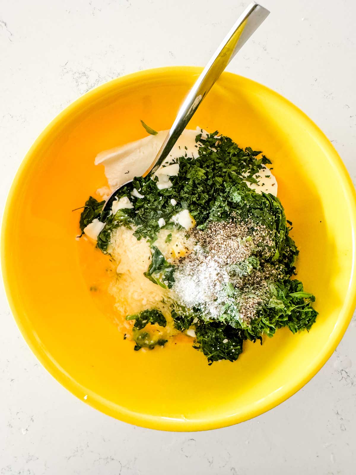 Ricotta, spinach, egg, and seasonings in a yellow bowl.