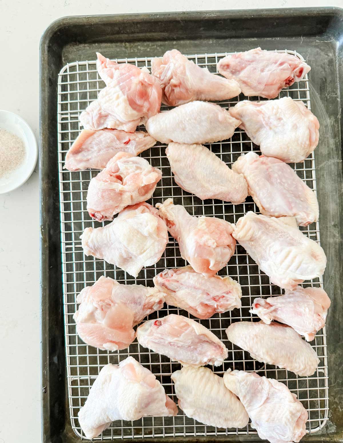 Overhead photo of salted chicken wings on a wire rack set on a baking sheet.