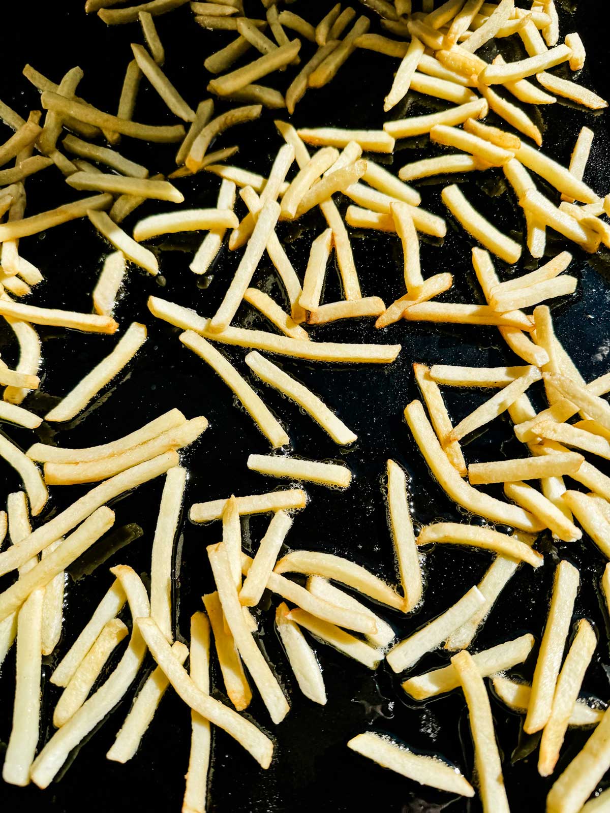 Frozen fries that have been added to oil on a Blackstone griddle.
