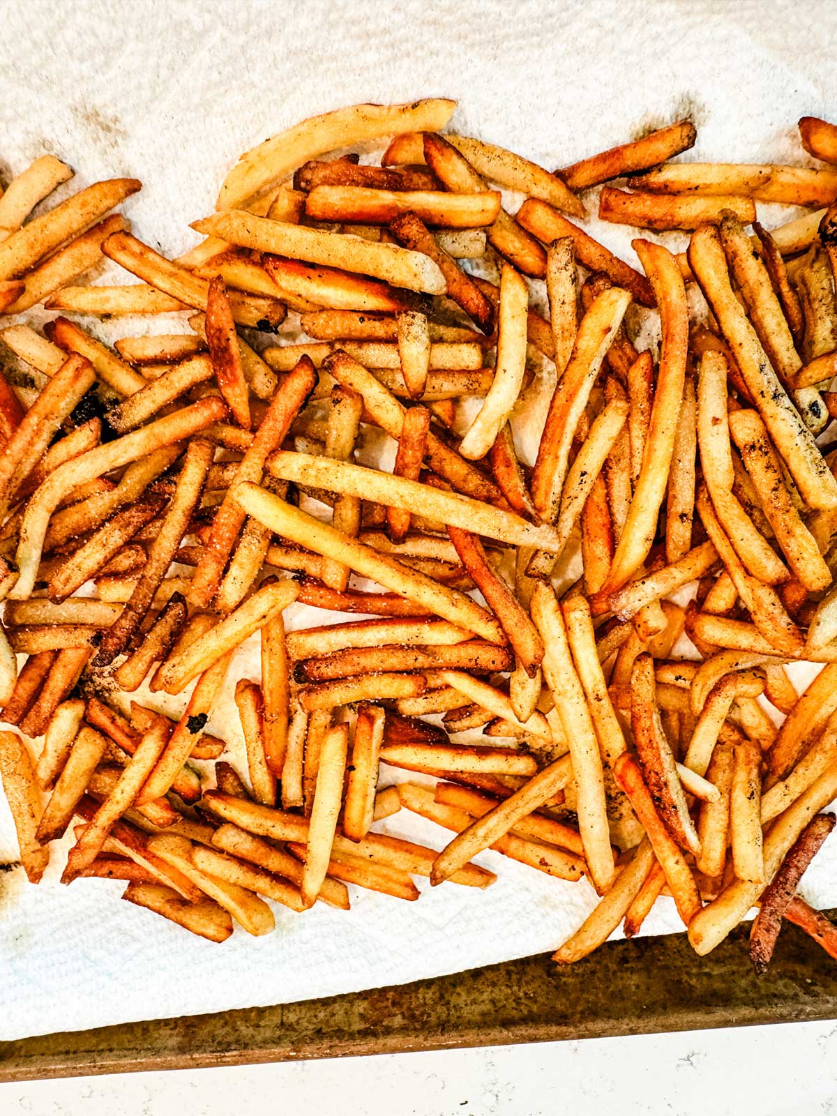 French fries on a paper towel lined baking sheet.