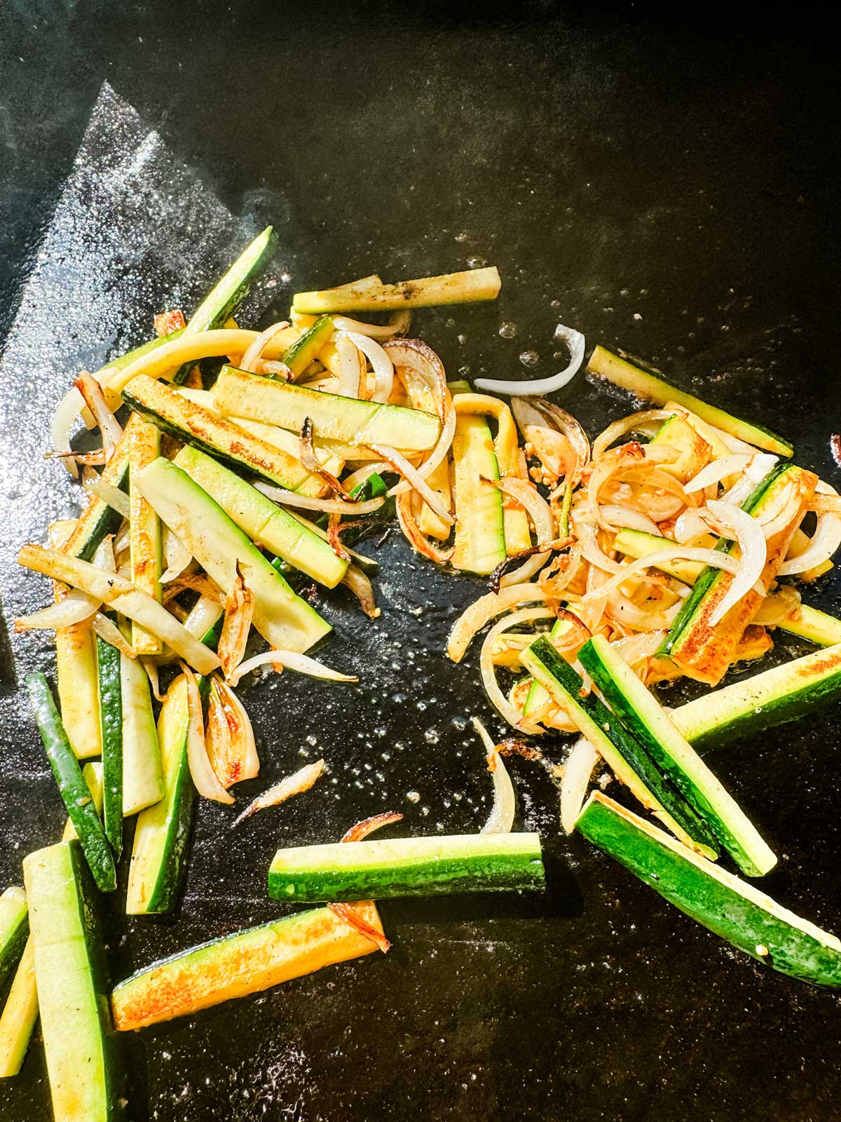Hibachi vegetables that are cooked and ready to take off a flat-top griddle.