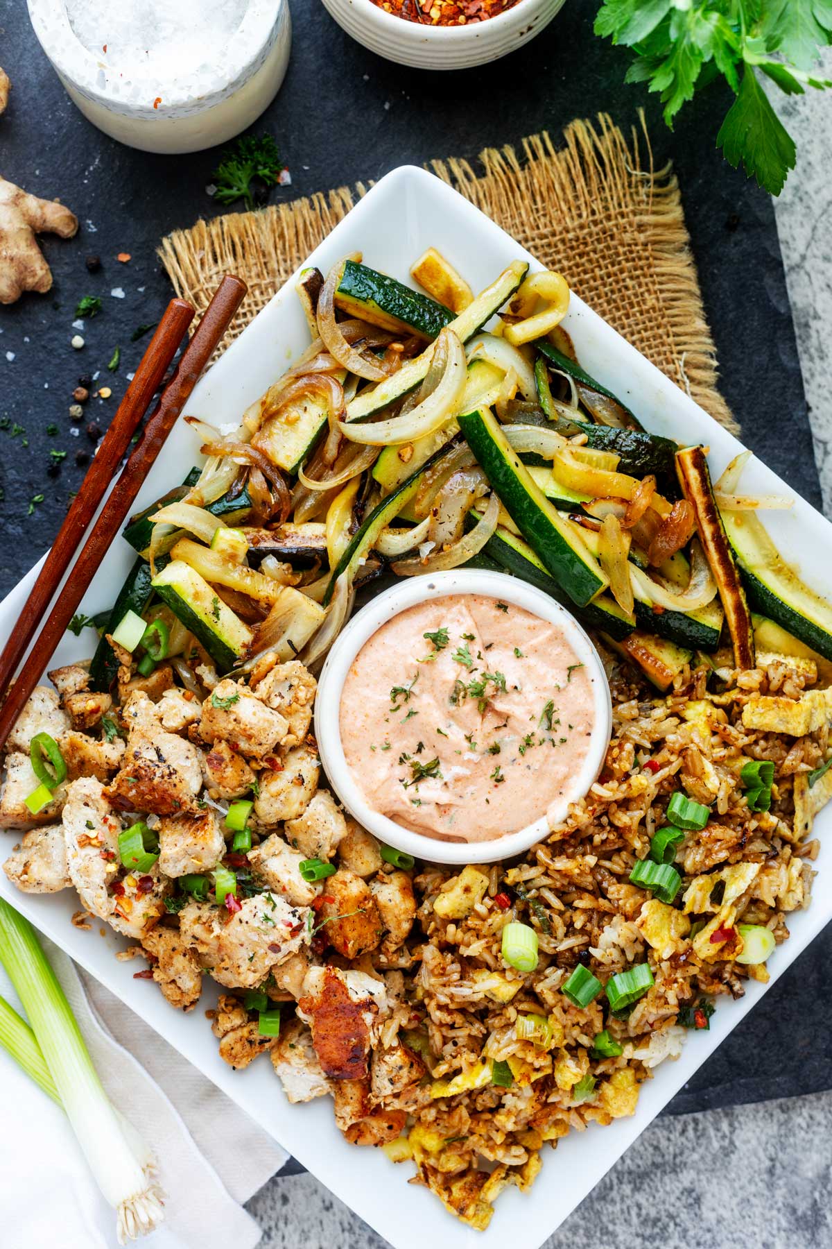 Overhead photo of Blackstone Hibachi chicken and vegetables on a square plate with Hibachi Rice.