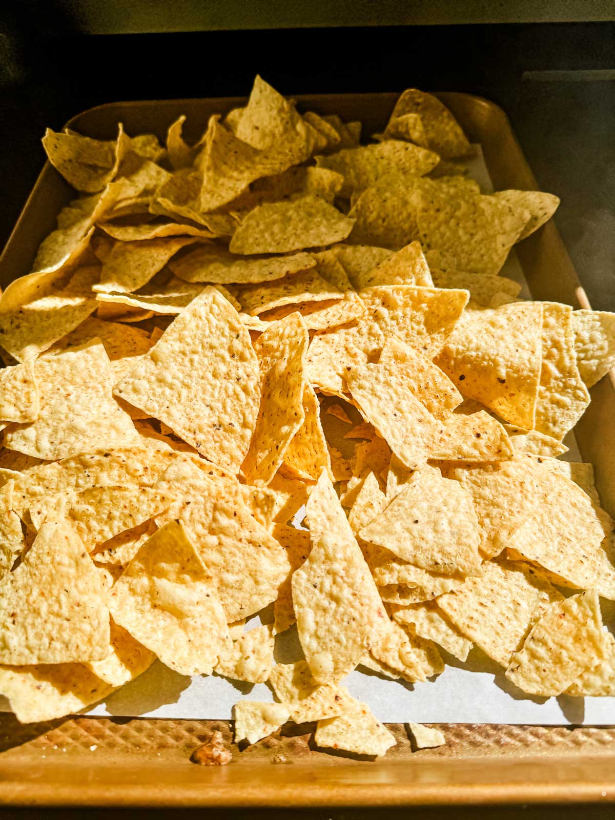 Tortilla chips on a parchment lined baking sheet.