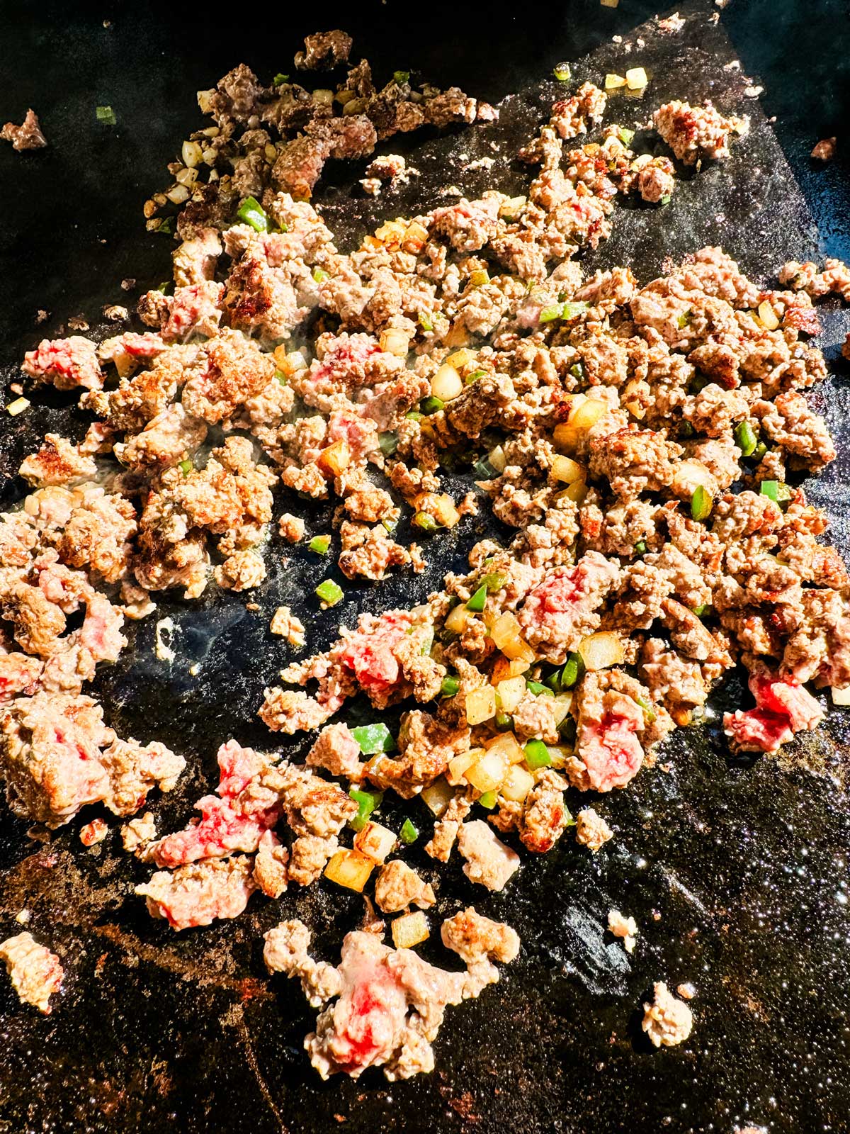 Ground beef cooking on a Blackstone griddle.