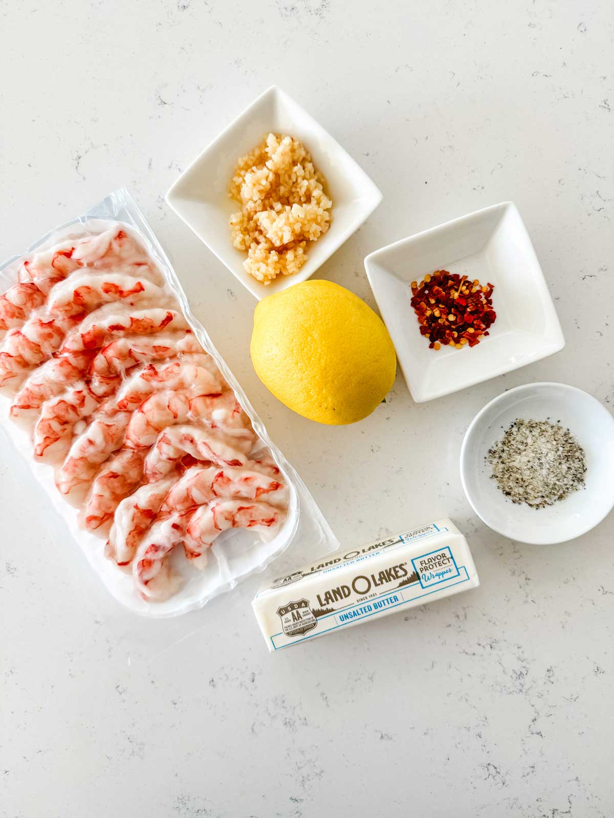 Overhead photo of shrimp, butter, garlic, lemon, and seasonings.