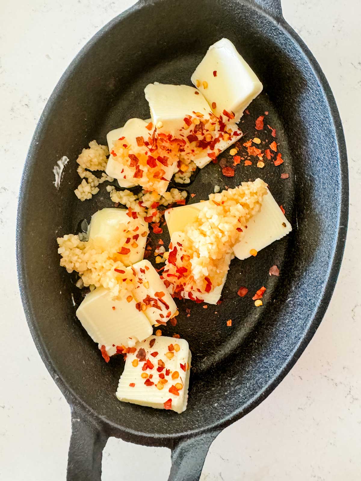 Photo of butter cubes and seasonings in a cast iron dish.